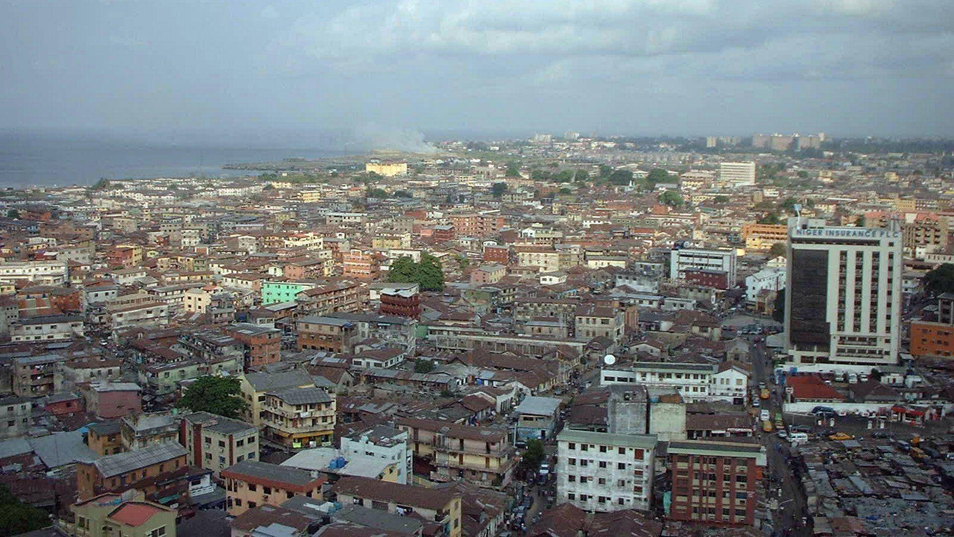 Nigeria 桌布 壁紙 — 在陰天之下，密集建築物與遠處海岸線的廣闊城市景觀。
