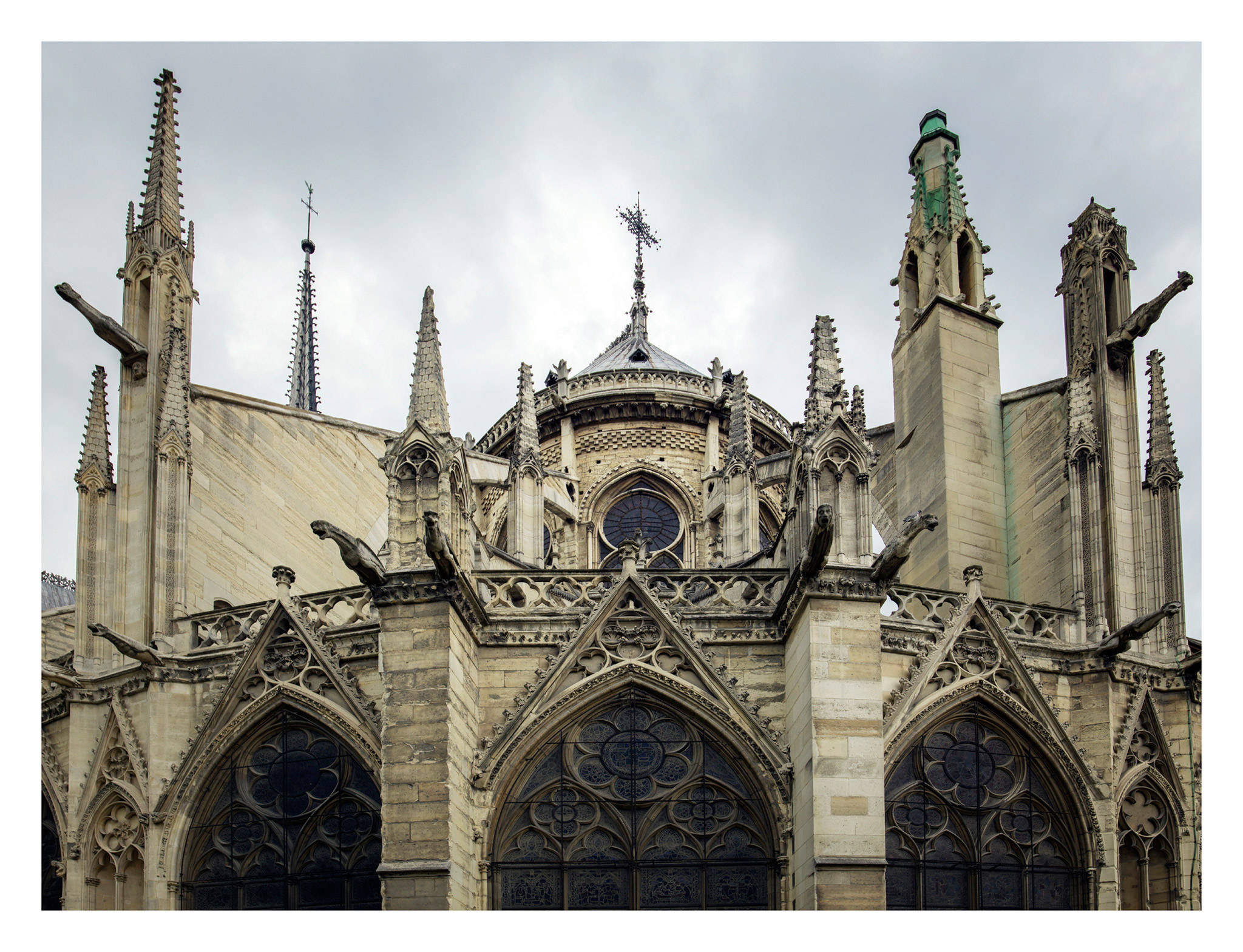 Notre Dame 桌布 壁紙 — 在陰天天空下，以戲劇性的低角度拍攝哥德式大教堂華麗的石頭外牆、飛扶壁和滴水嘴獸。