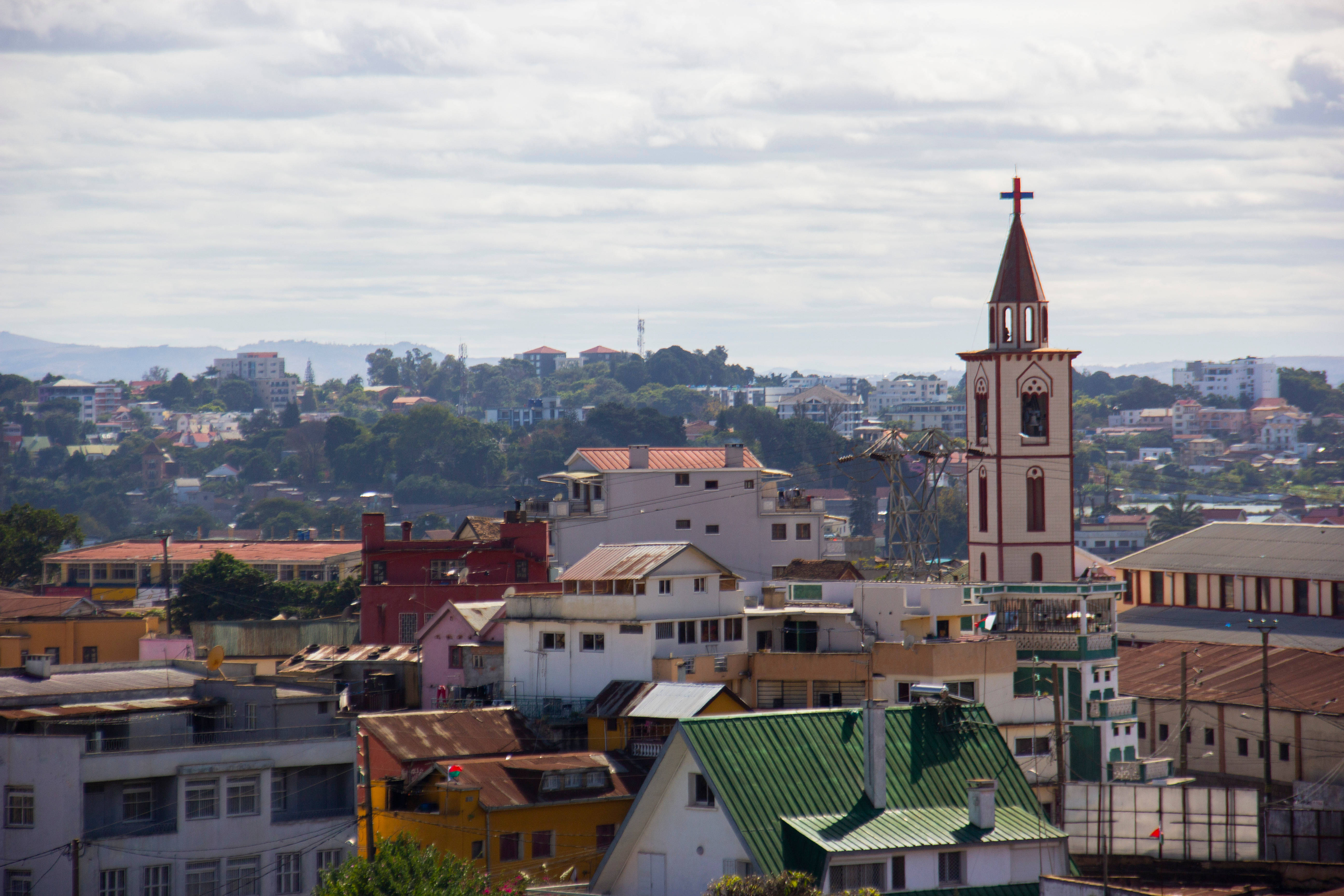 Madagascar 桌布 壁紙 — 在陰天天空下，充滿活力的城市景觀，色彩繽紛的建築物和突出的教堂塔樓。