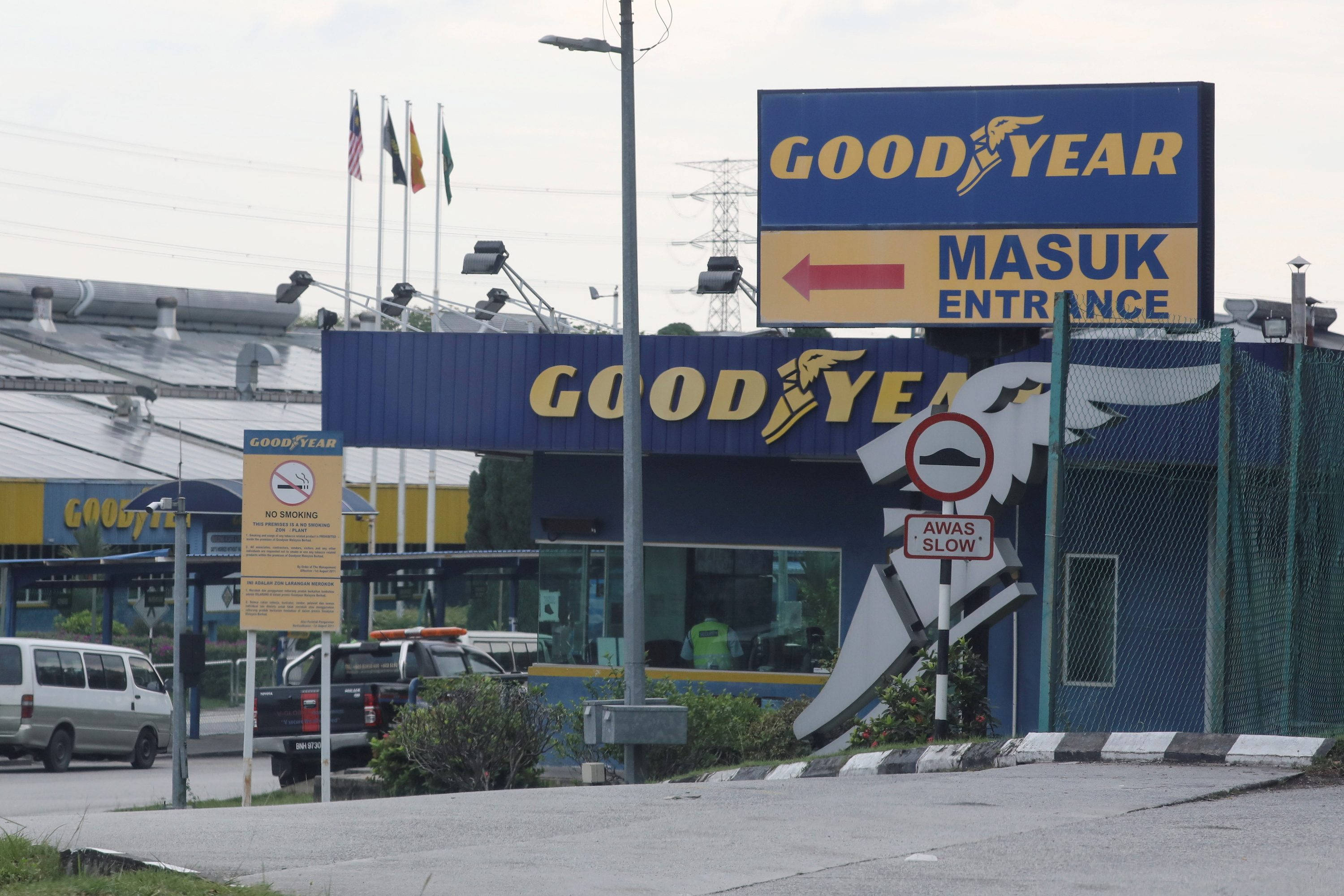 Malaysia 桌布 壁紙 — 在陰天天空下，帶有藍色標誌和停放車輛的Goodyear輪胎店入口。
