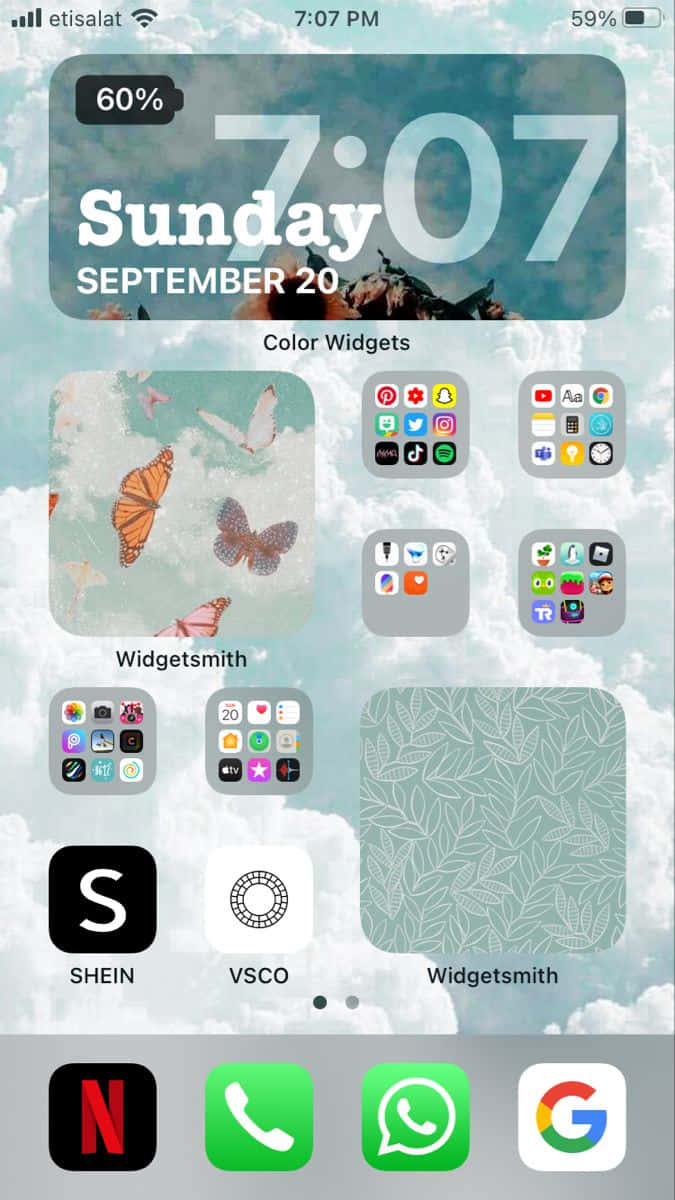 iPhone 美學 桌布 壁紙 — 在陰天天空下，帶有蝴蝶桌布和應用程式小工具的 iPhone 主畫面。