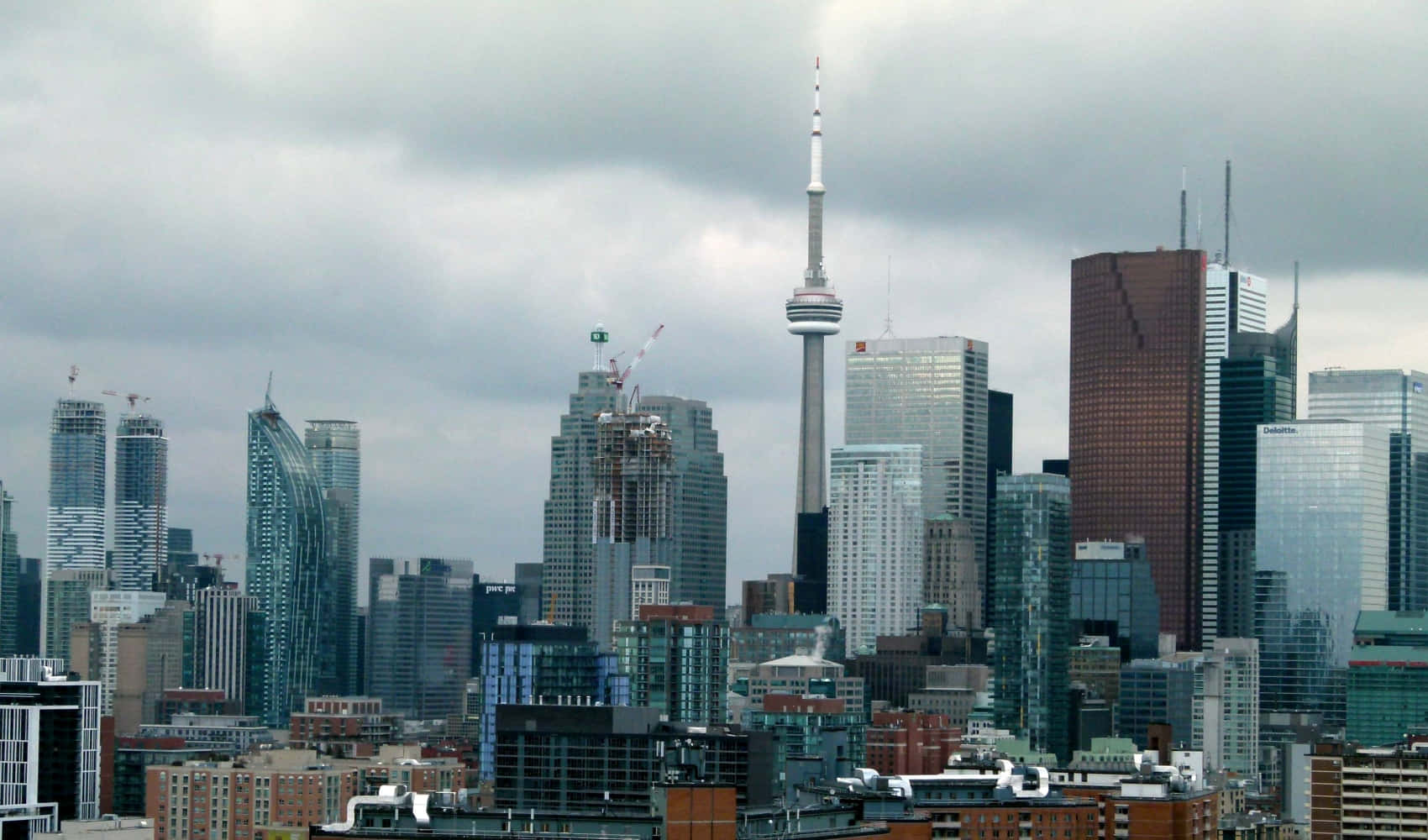 Toronto Skyline 桌布 壁紙 — 在陰天籠罩下，廣闊的城市天際線以標誌性的CN塔和現代玻璃摩天大樓為主導。