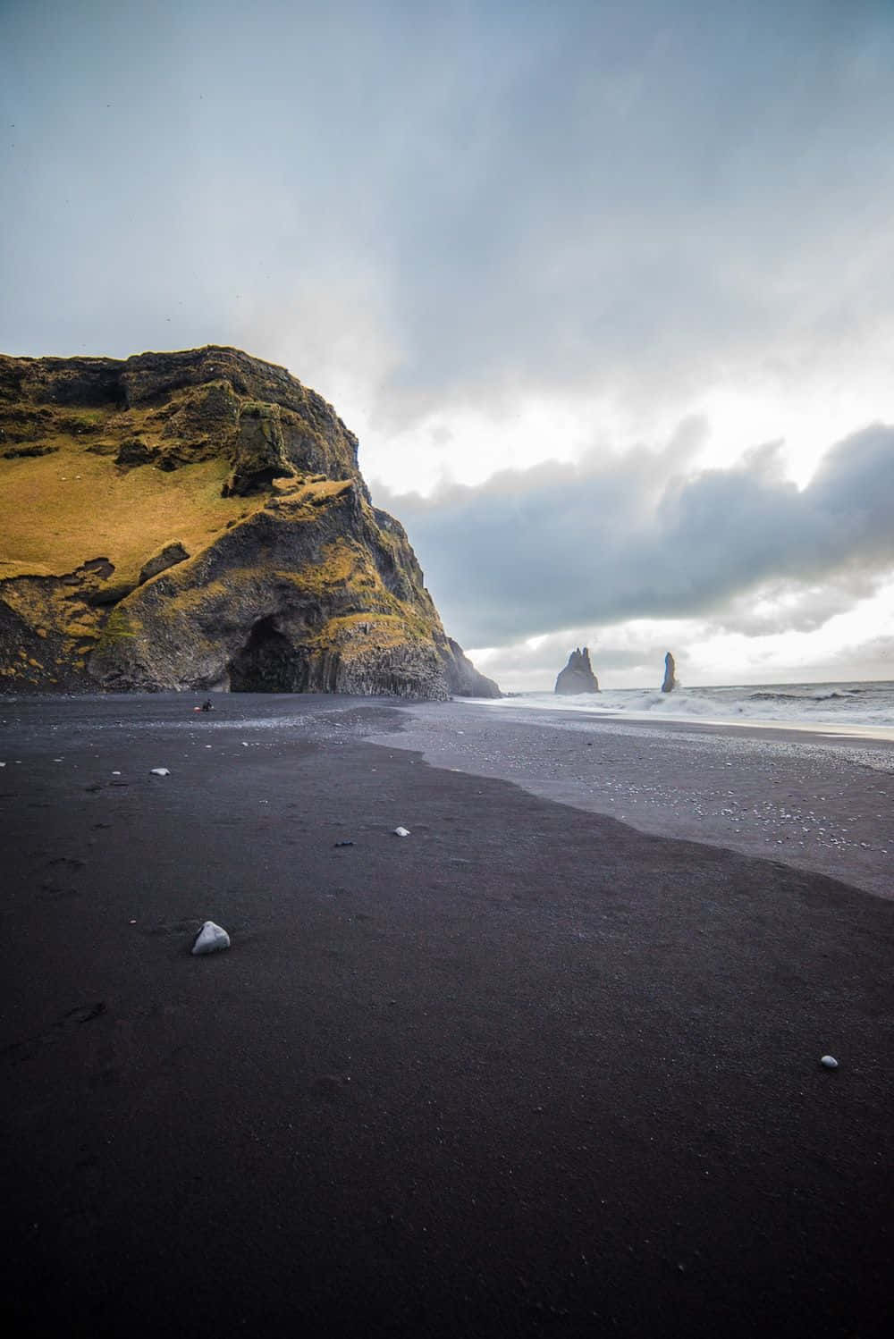 Black Sand Beach 桌布 壁紙 — 在陰沉多雲的天空下，一個戲劇性的黑沙灘，有高聳的懸崖和海蝕柱。