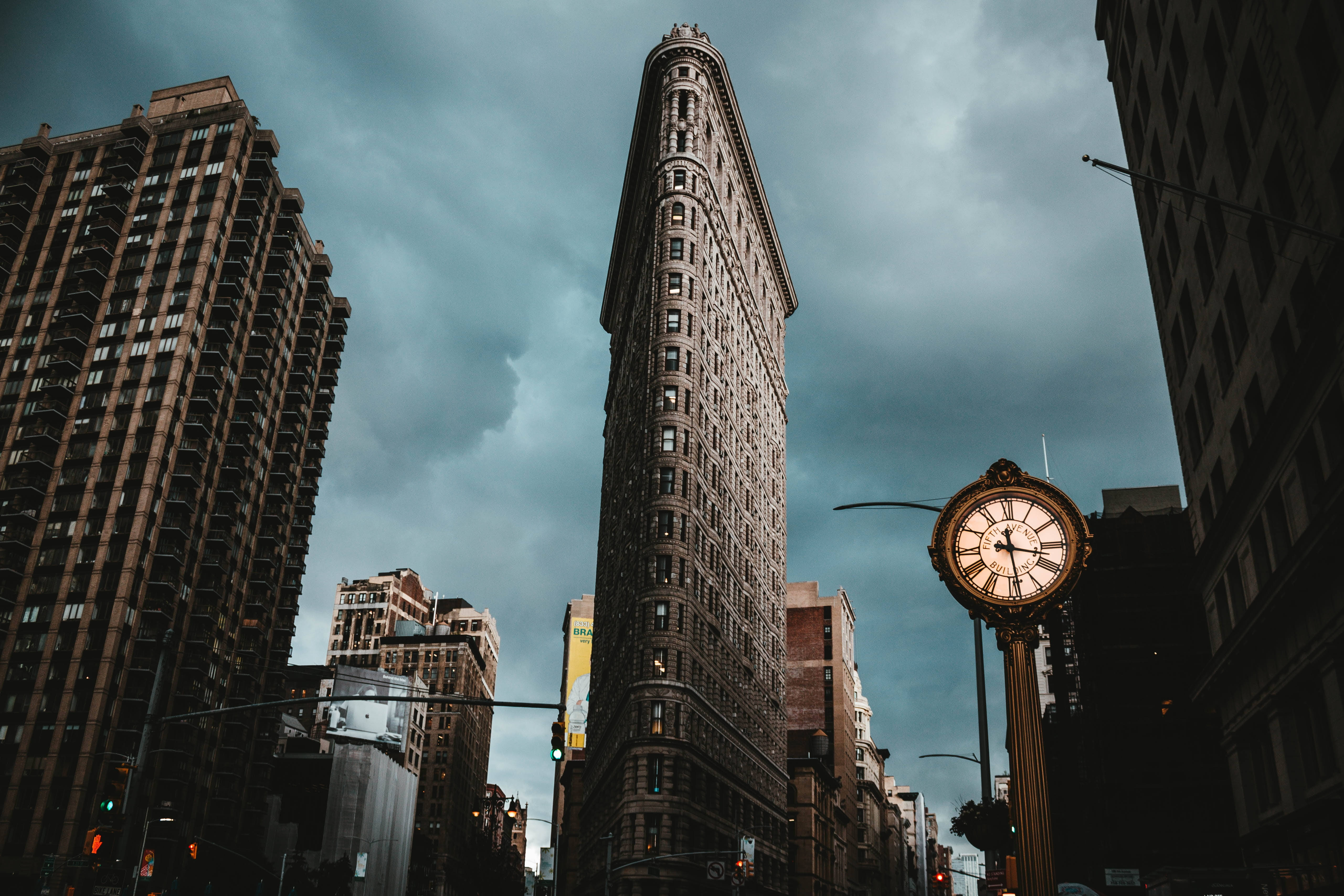 New York 桌布 壁紙 — 在陰沉灰暗的天空下，以低角度拍攝紐約市標誌性的熨斗大廈，前景有一個復古街頭時鐘。