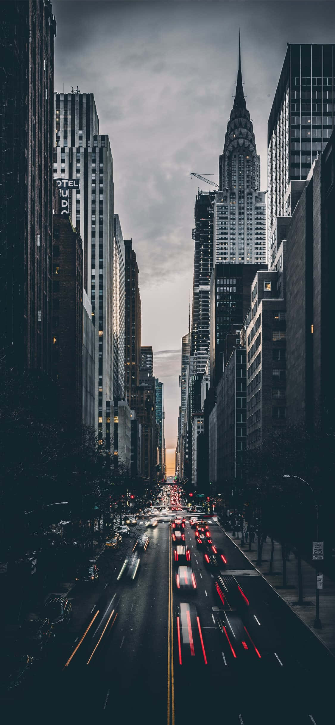 New York 桌布 壁紙 — 在陰沉的暮色天空下，車流在摩天大樓之間穿梭，形成光軌的戲劇性都市峽谷拍攝。