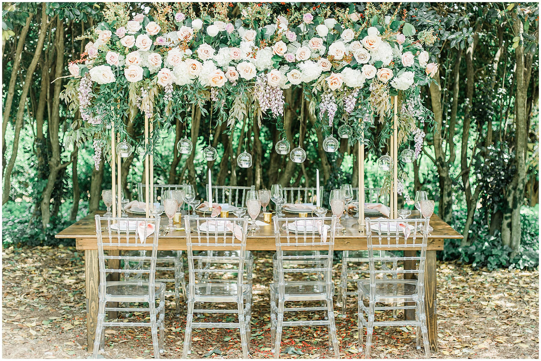Wedding Aesthetic 桌布 壁紙 — 在陽光明媚的森林中，一張木製餐桌在由白色和淡粉紅玫瑰組成的茂密花冠下為婚禮佈置。