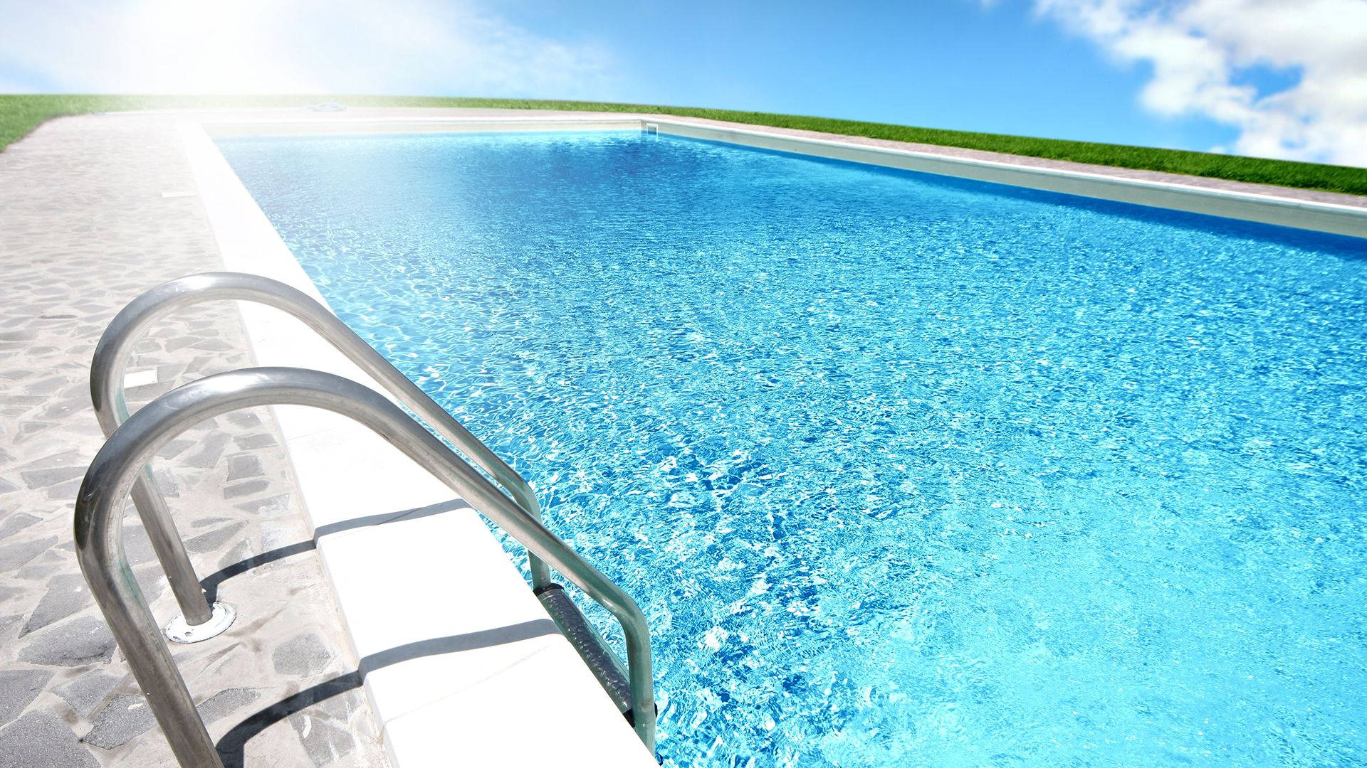 Swimming 桌布 壁紙 — 在陽光明媚的草地上，一個閃閃發光的藍色游泳池配有鉻製梯子。
