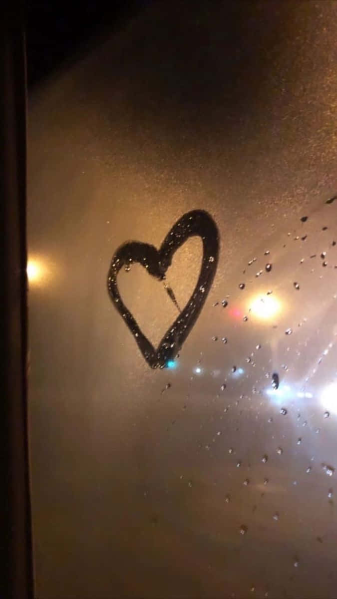 心形美學 桌布 壁紙 — 在雨中窗上畫的心形，溫暖發光的燈光透過濕玻璃反射。