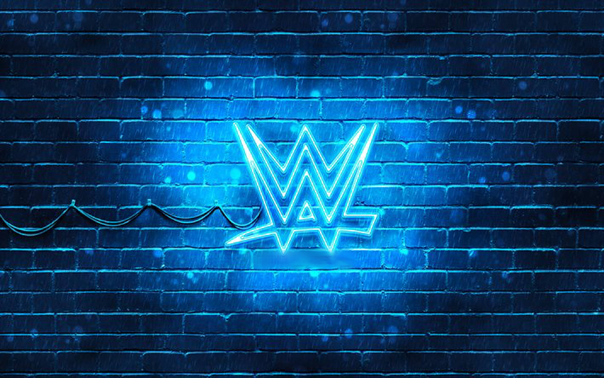 WWE 桌布 壁紙 — 在雨夜條件下，發光的藍色霓虹WWE標誌在潮濕的磚牆上明亮閃耀。