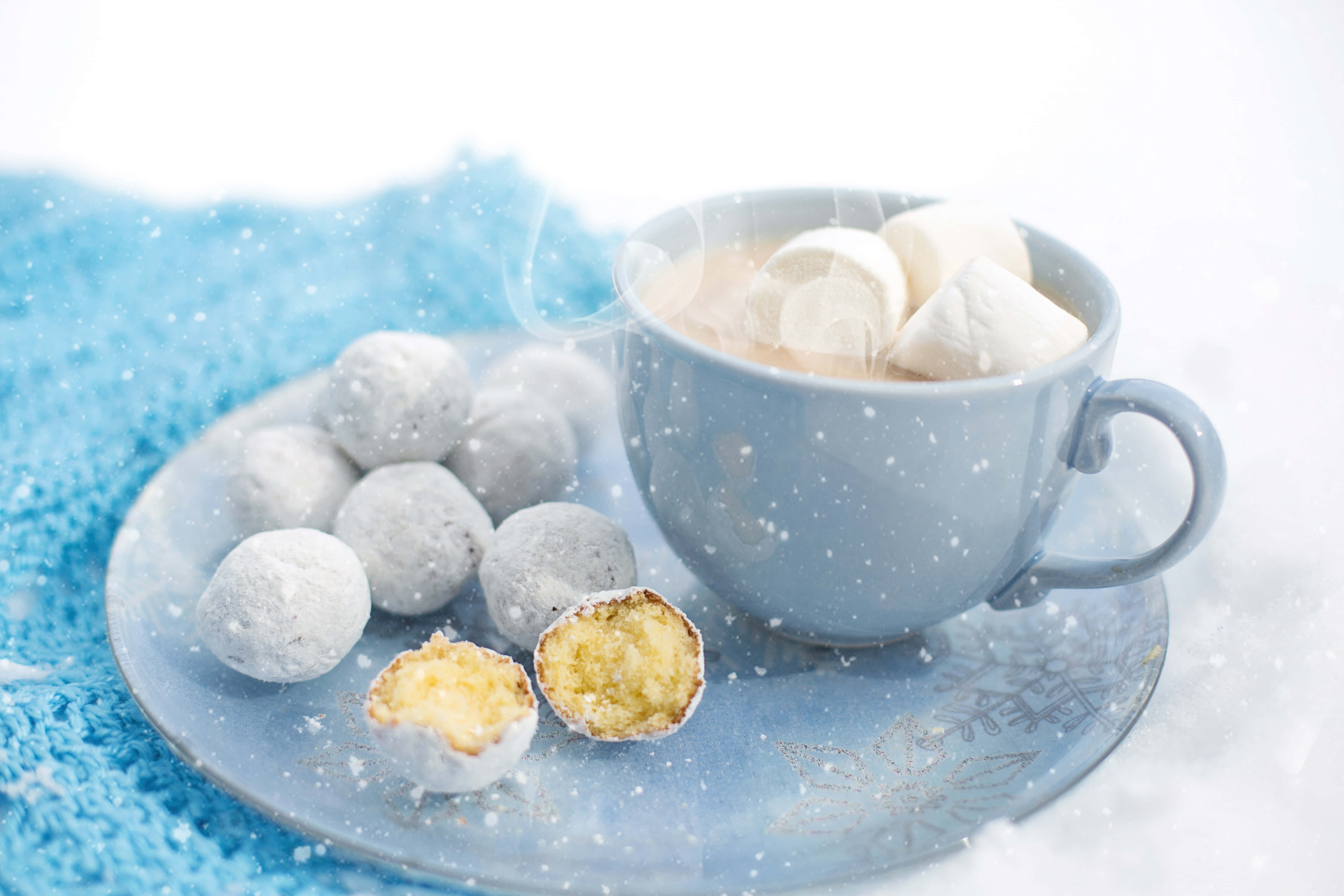 Hot Chocolate 桌布 壁紙 — 在雪景背景下，藍色盤子上放著一杯冒熱氣的熱巧克力，搭配棉花糖和糖粉包裹的甜點。
