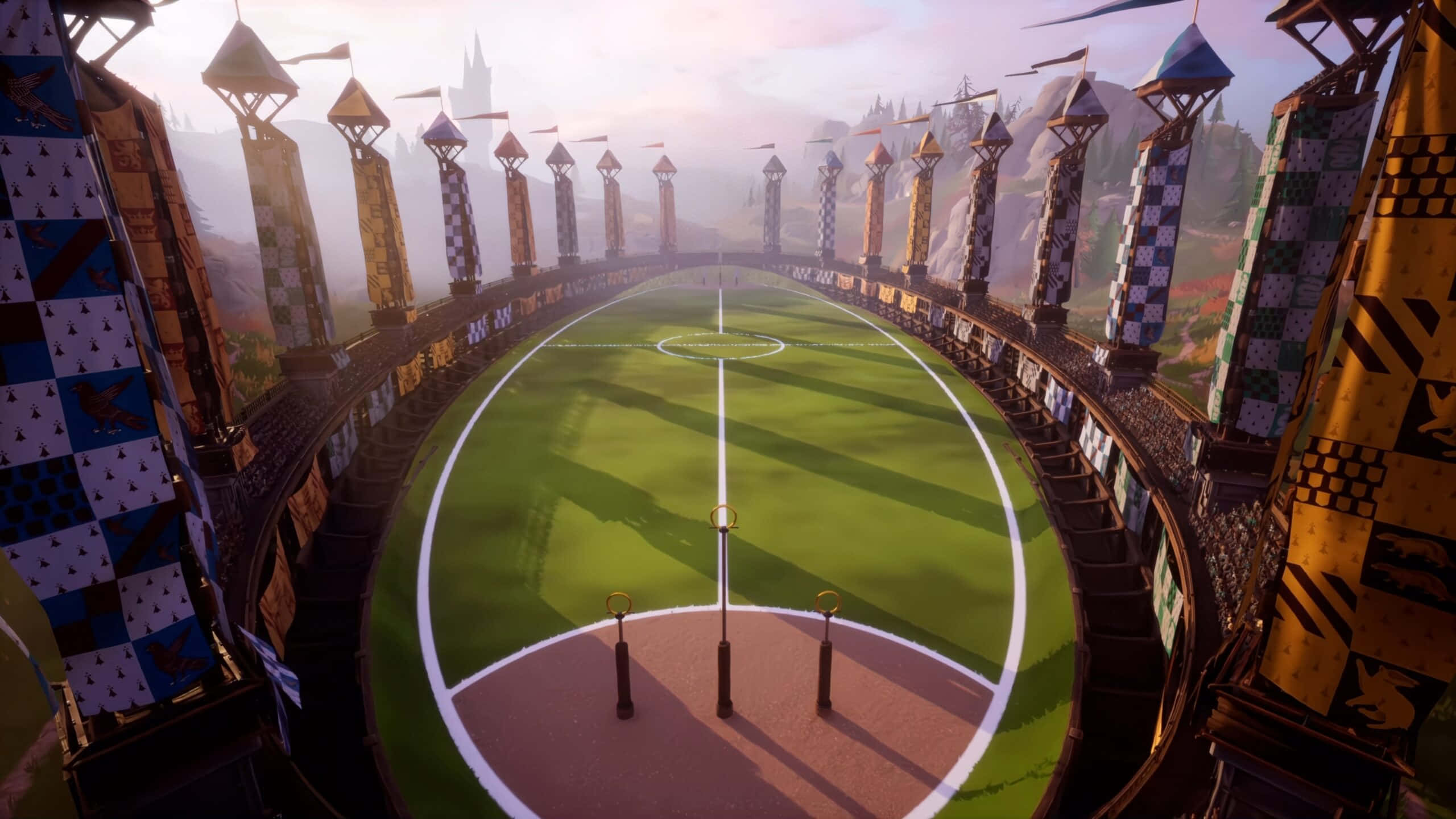 The Hogwarts Quidditch Pitch 桌布 壁紙 — 在霧氣瀰漫的黎明天空下，一個充滿活力的魁地奇球場，配有金色球環和格子旗幟。