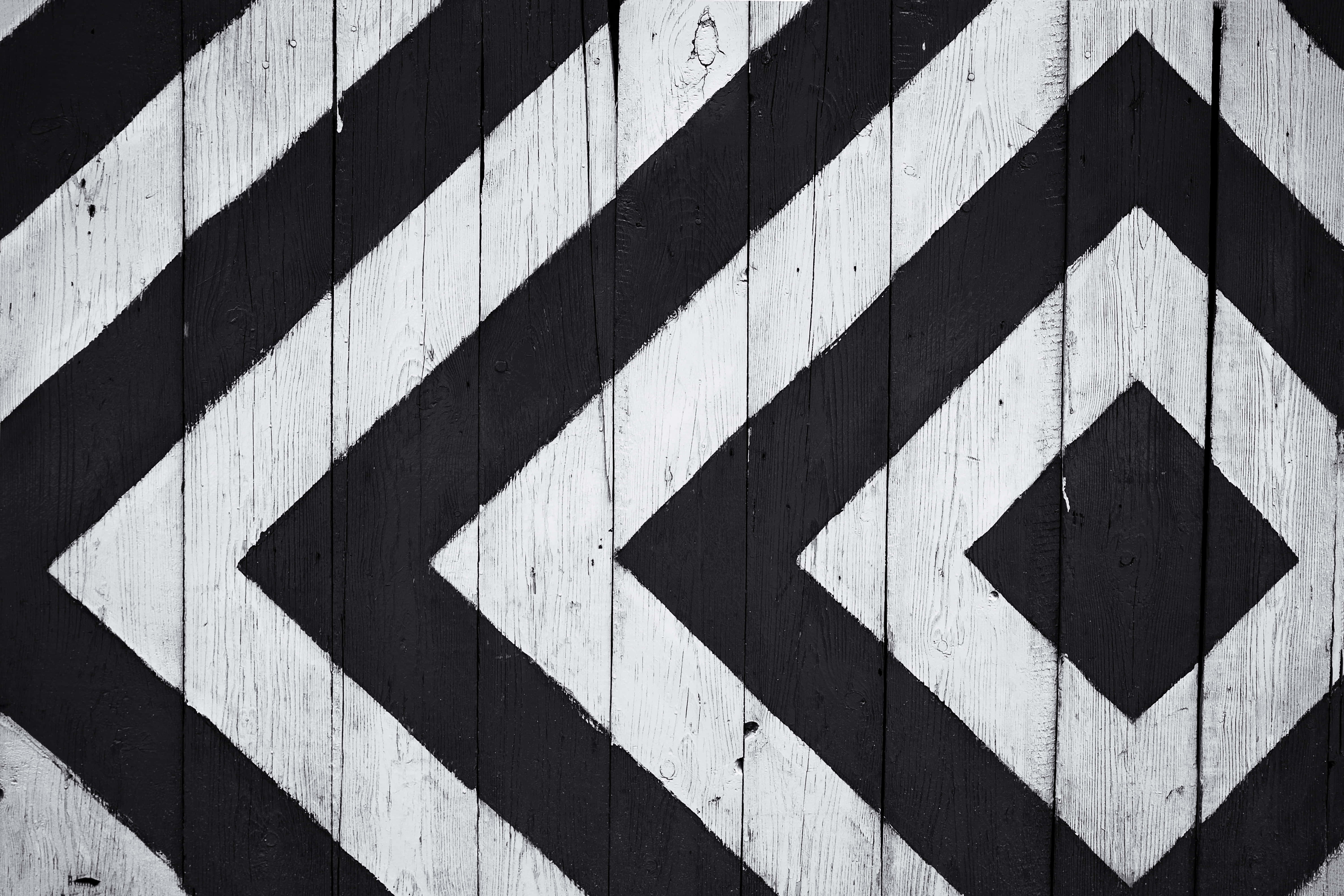 Black And White Abstract 桌布 壁紙 — 在風化木板上繪製的大膽黑白幾何菱形圖案，營造出引人注目的高對比抽象設計。