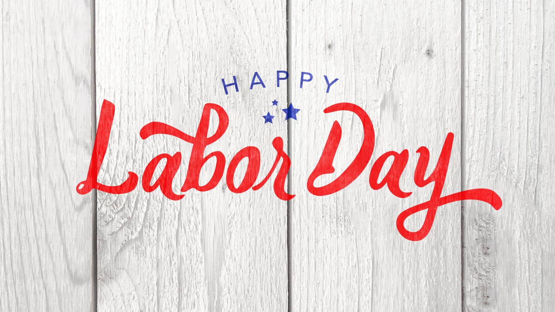 勞動節 桌布 壁紙 — 在風化的白色木板上，紅色和藍色的草書「Happy Labor Day」文字，帶有星星。