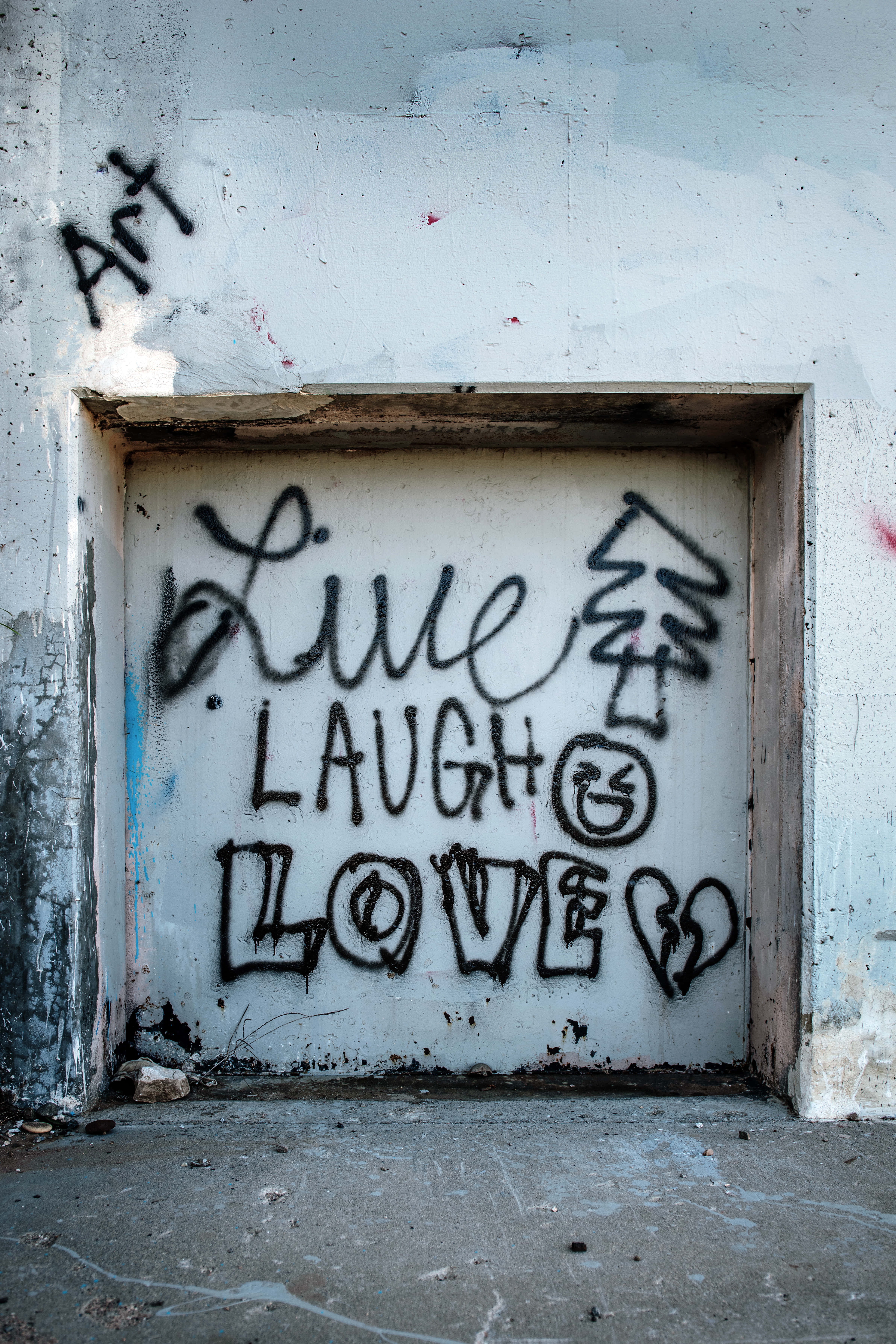 Live Laugh Love 桌布 壁紙 — 在風化的白色門上，塗鴉以粗體黑色噴漆寫著「live laugh love」並帶有笑臉。