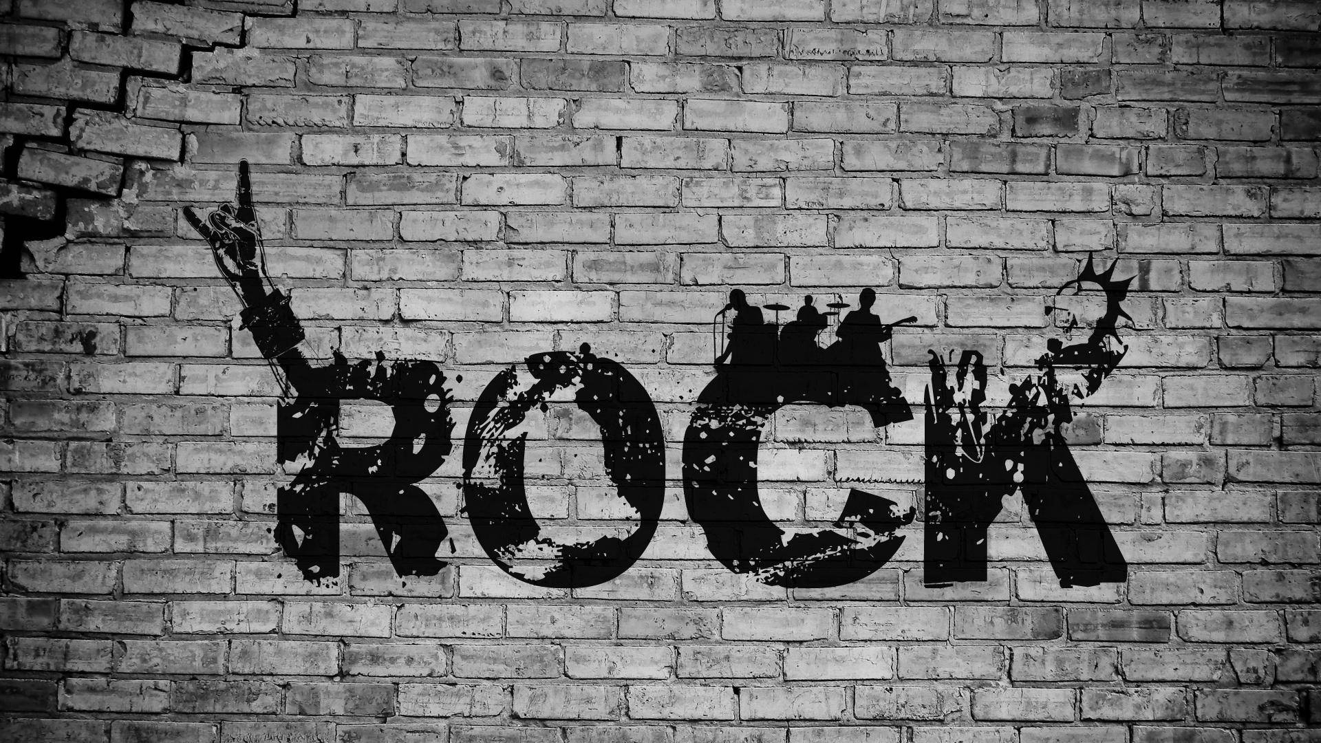 Rock 桌布 壁紙 — 在風化的磚牆上，大膽的黑色塗鴉拼寫出「ROCK」，並有樂隊剪影和高舉的手。