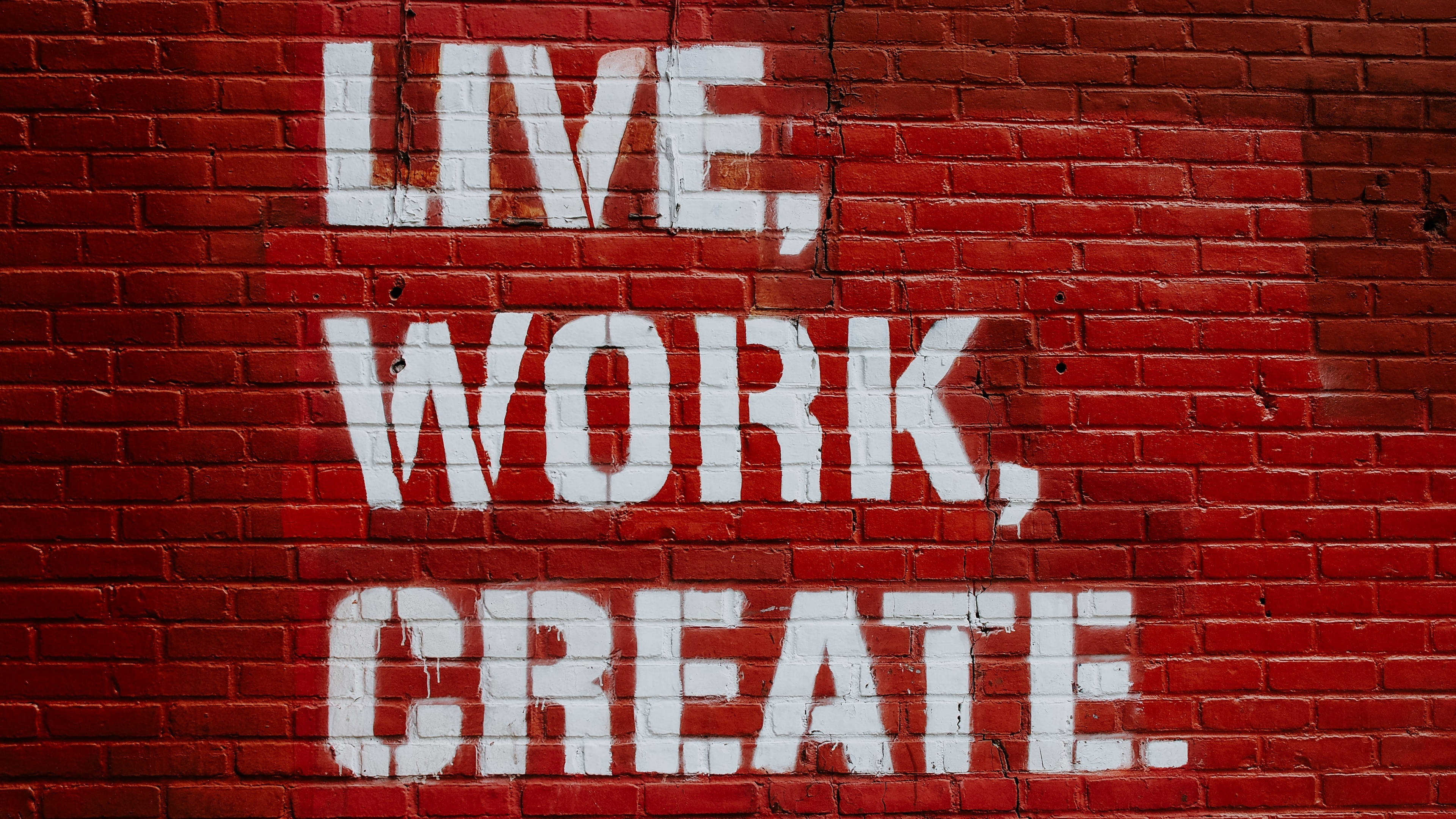 Work 桌布 壁紙 — 在風化的紅磚牆上，塗有醒目的白色塗鴉文字，寫著 live work create。