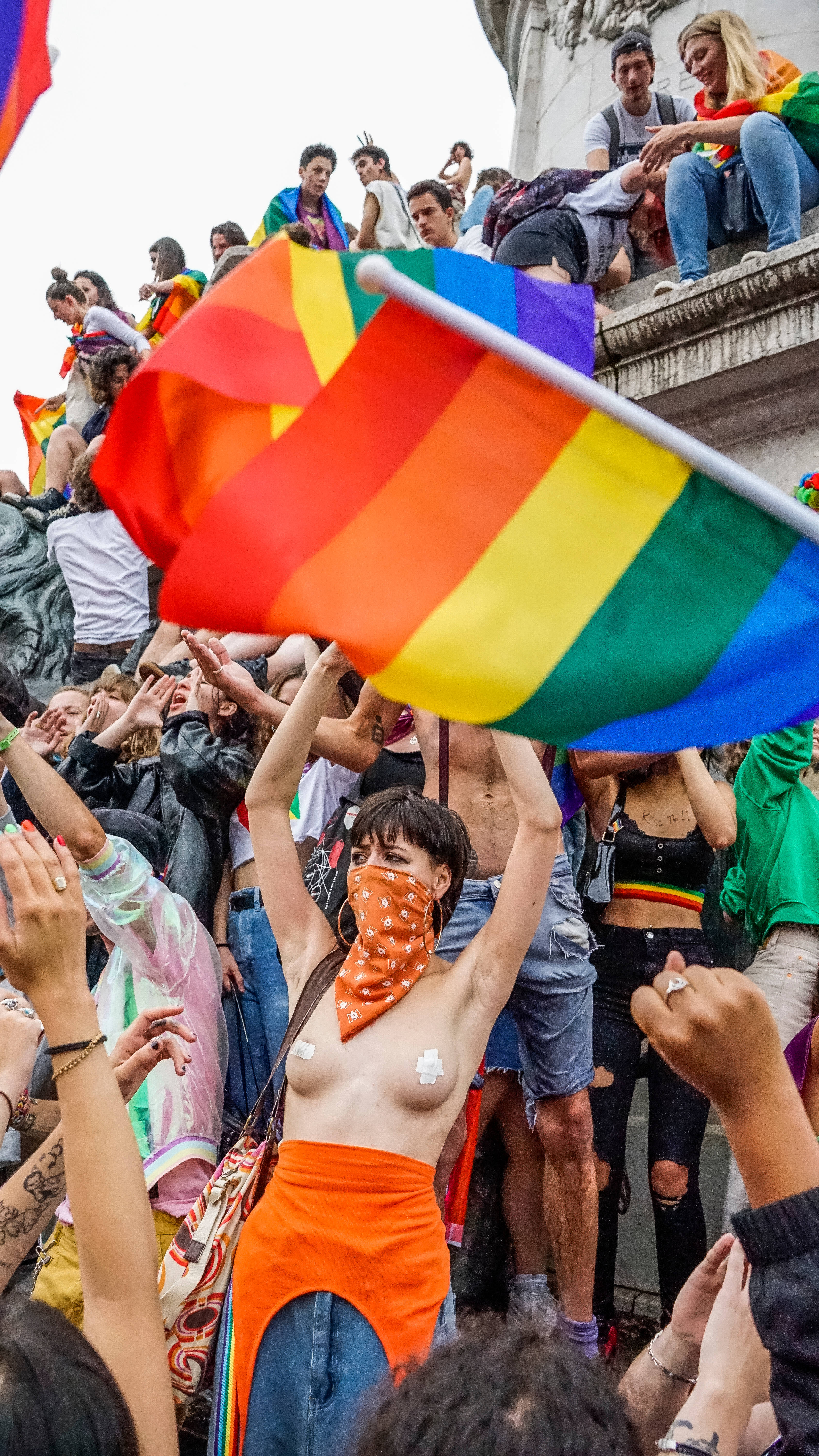 女同志 桌布 壁紙 — 在驕傲遊行中，充滿活力的人群揮舞著彩虹旗，在明亮的日光下以歡樂的能量歡呼。