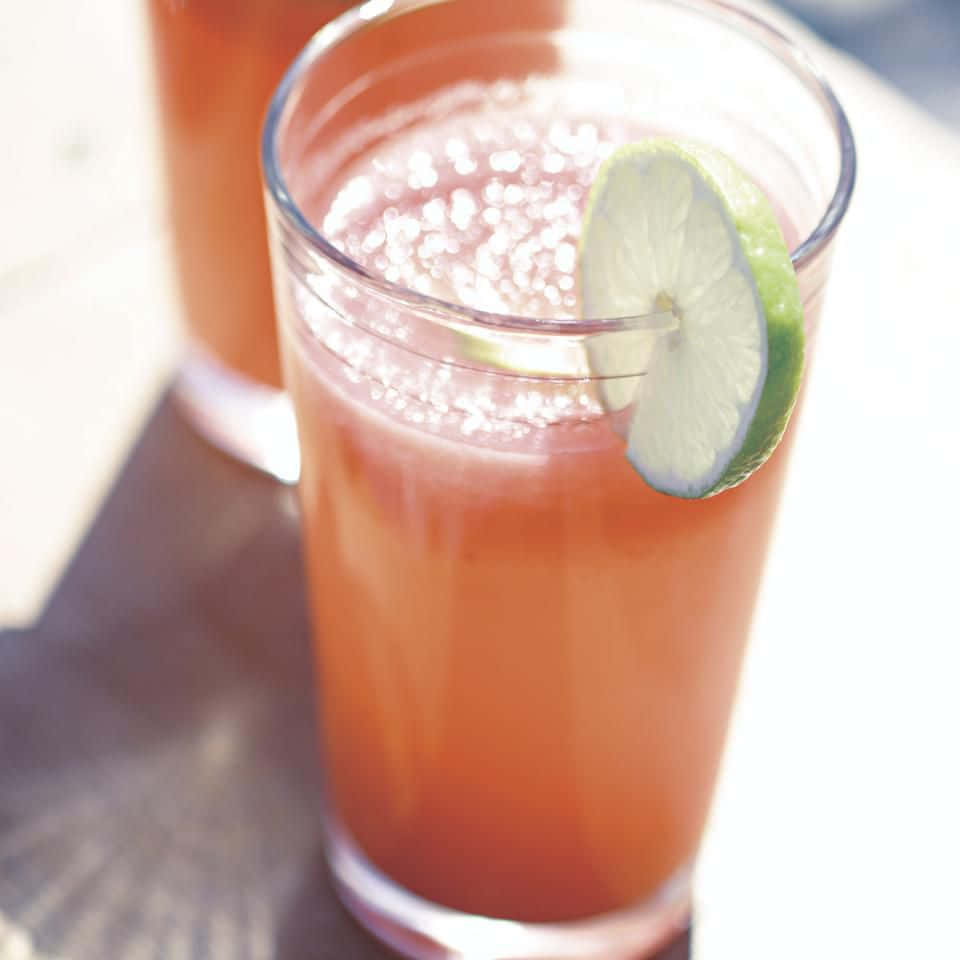 高腳杯中，一款粉紅色飲品，配上萊姆裝飾和冰塊氣泡。 — Juice Wrld 壁紙