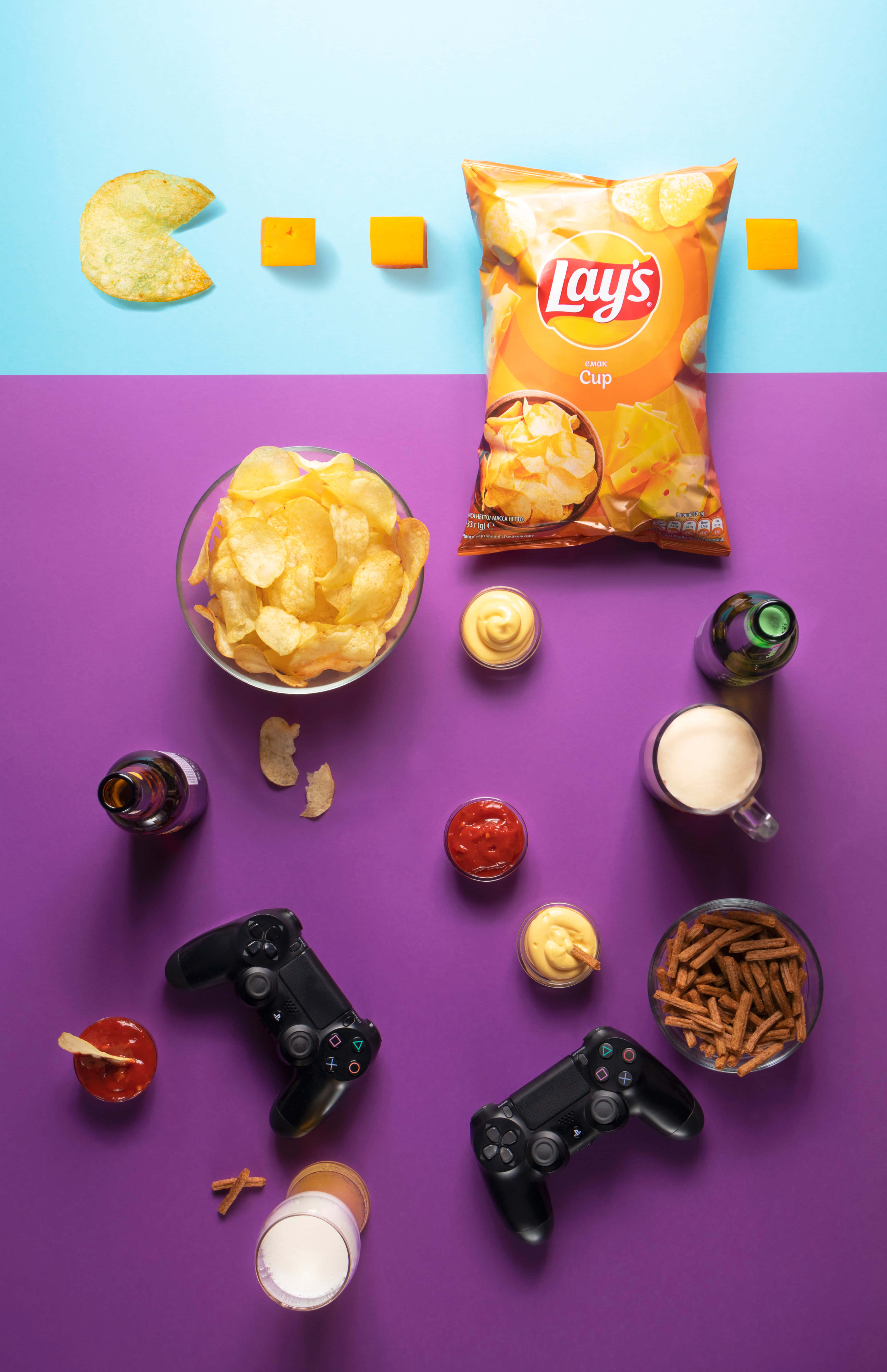 Snacks 桌布 壁紙 — 在鮮豔的紫色和藍色背景上，以平鋪方式擺放遊戲零食和控制器。