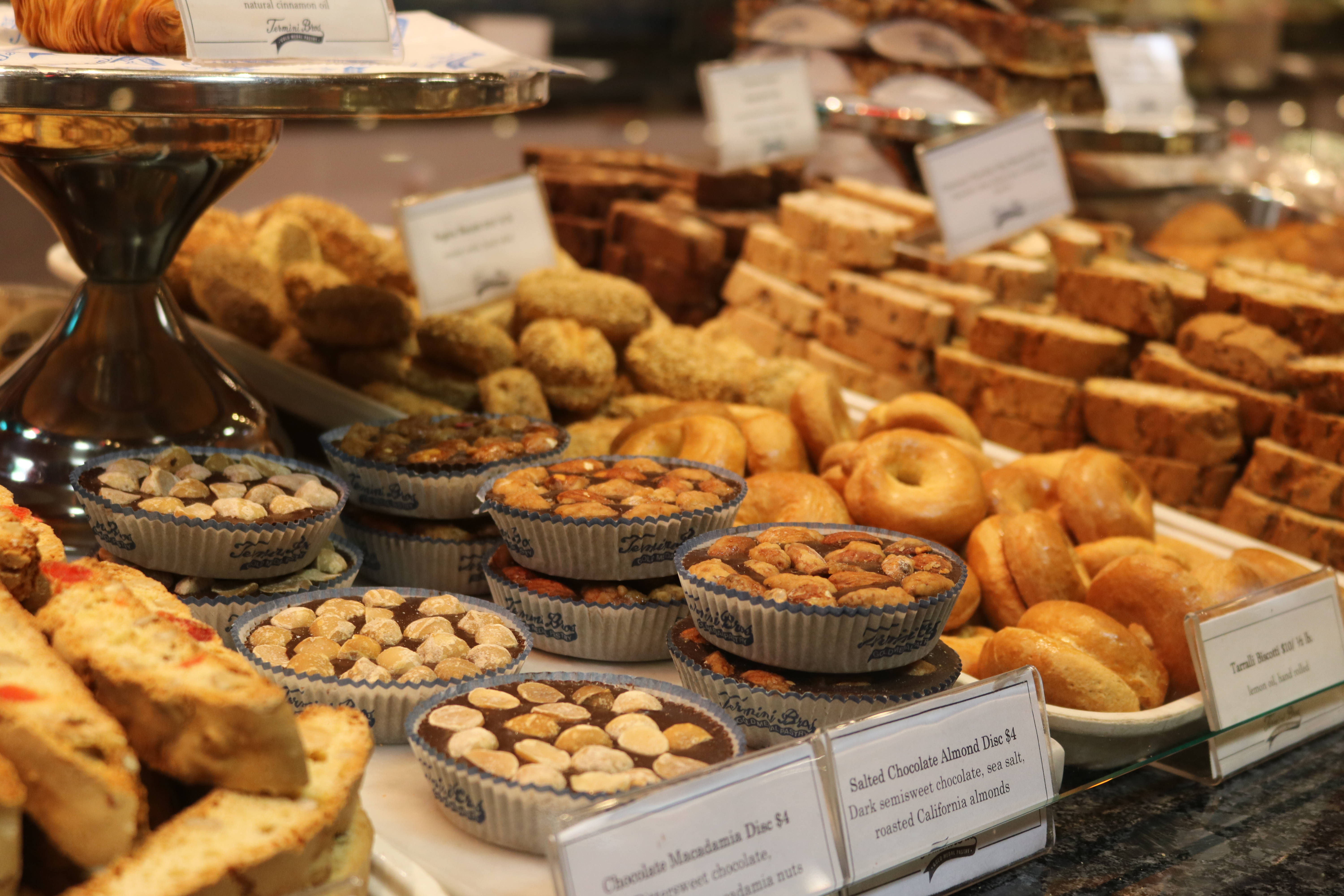 Pastries 桌布 壁紙 — 在麵包店中，多層托盤上擺放著各式糕點和麵包，並附有價格標籤，誘人展示。