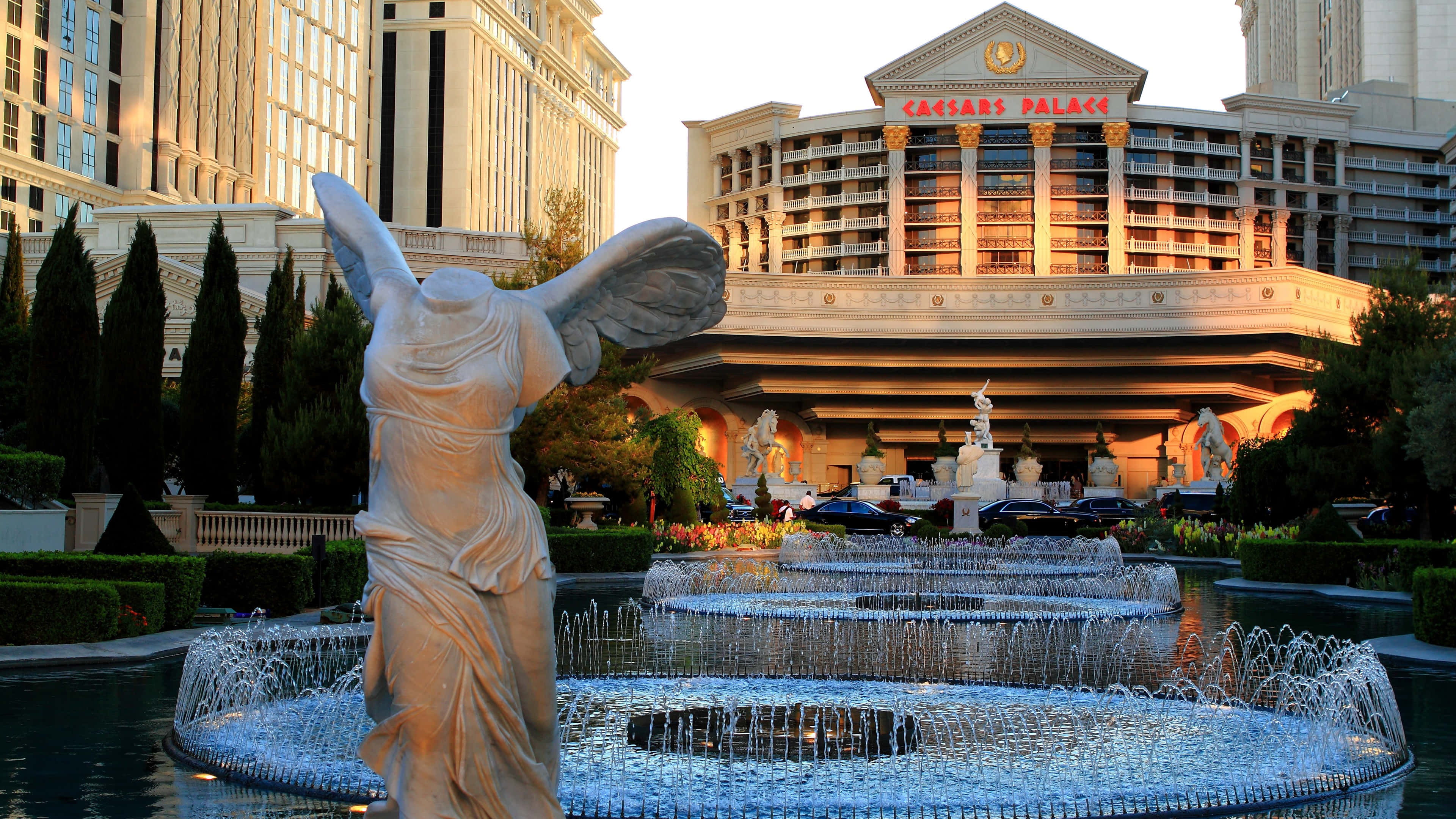 4K Las Vegas 桌布 壁紙 — 在黃金時段，一座宏偉的大理石天使雕像矗立在凱撒宮酒店入口處的層疊噴泉前。
