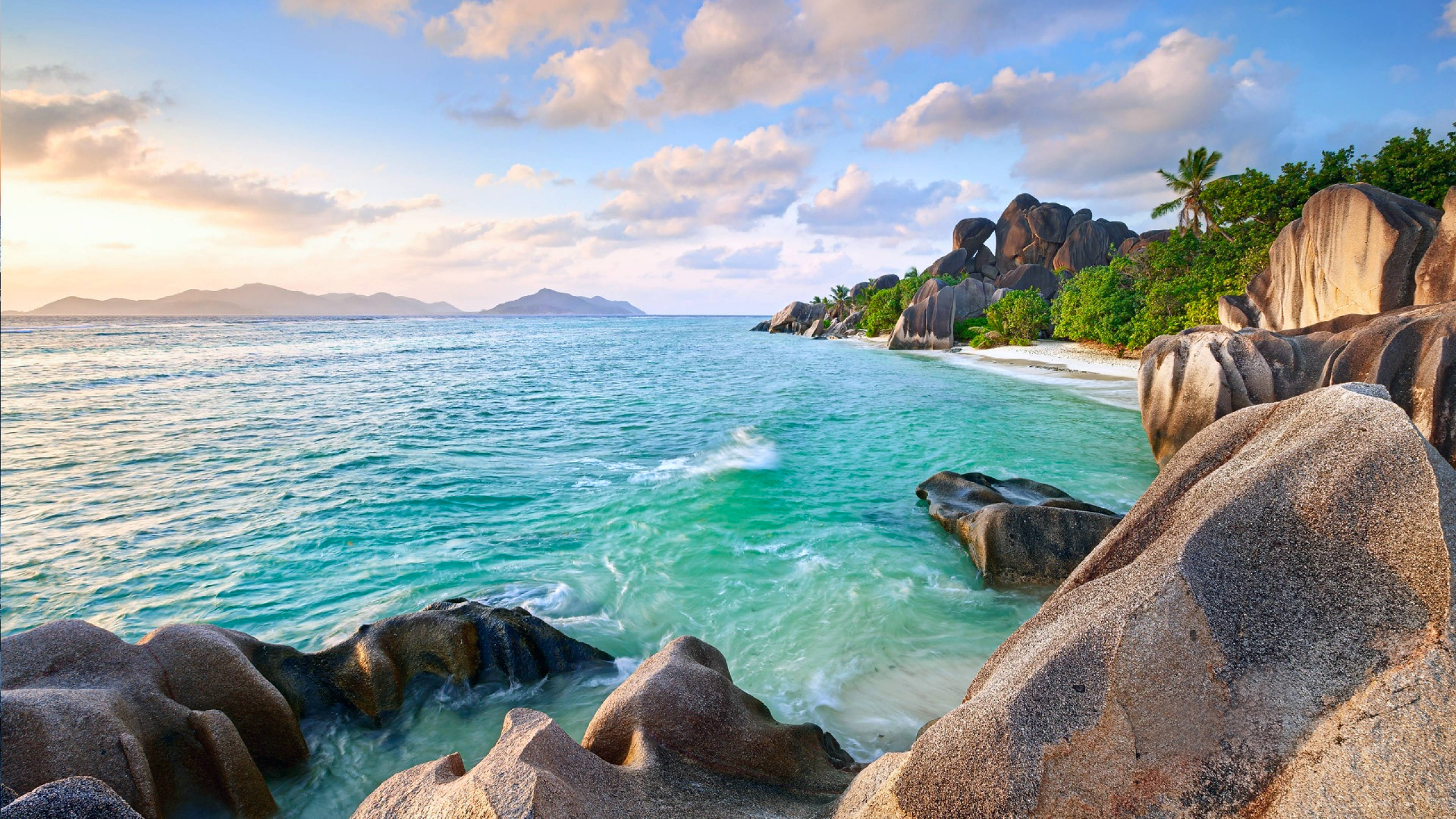 4K Summer 桌布 壁紙 — 在黃金時段，碧綠的海水拍打著偏遠熱帶海灘上的巨大花崗岩巨石。