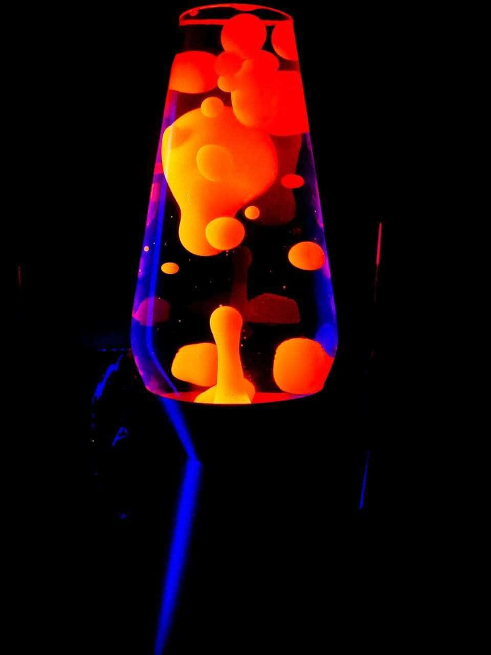 lava lamp 桌布 壁紙 — 在黑暗中緩慢上升的橙色和藍色塊狀物的發光熔岩燈。