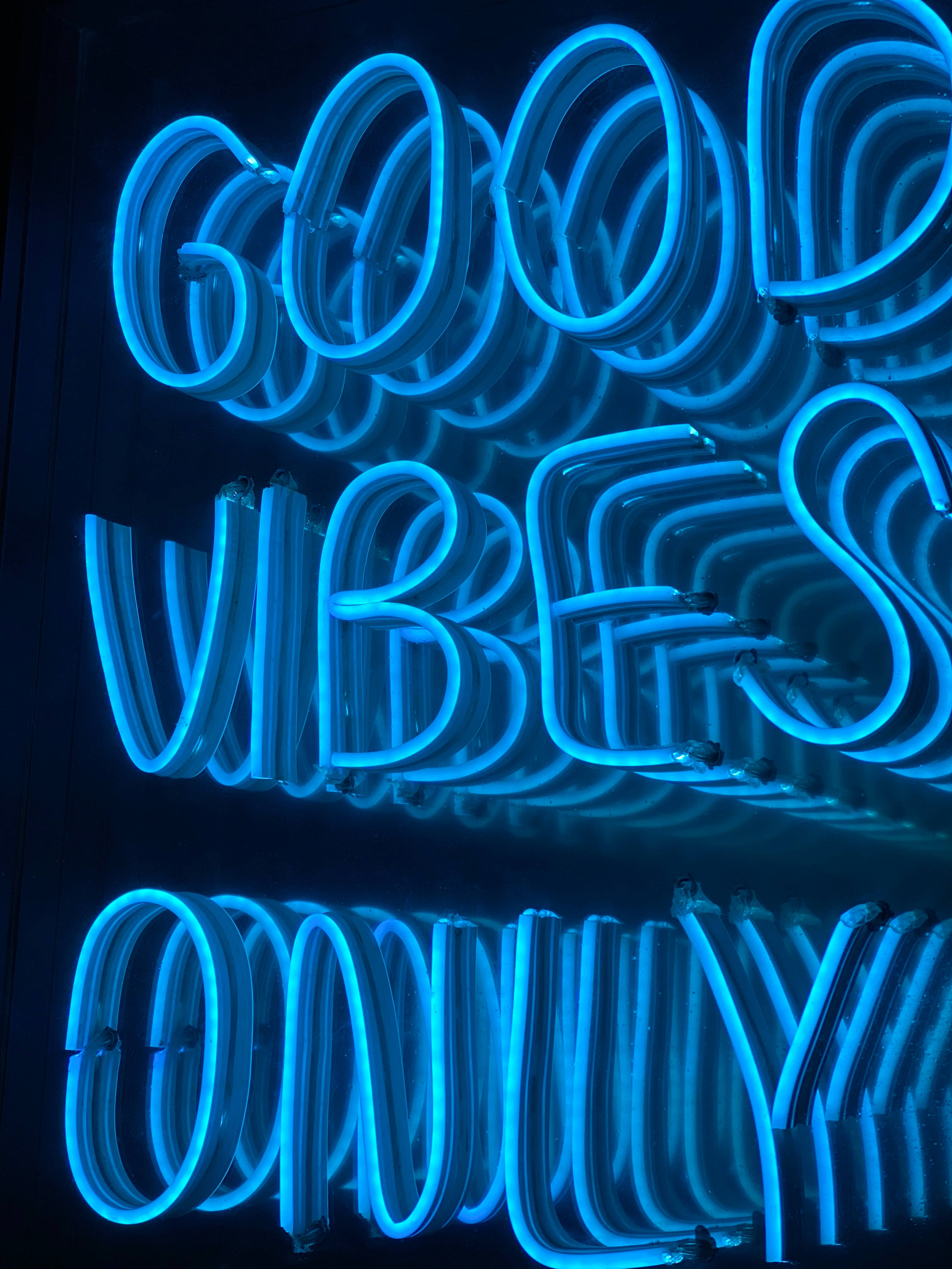 Feels 桌布 壁紙 — 在黑暗反光表面上，發光的藍色霓虹燈牌顯示「good vibes only」。