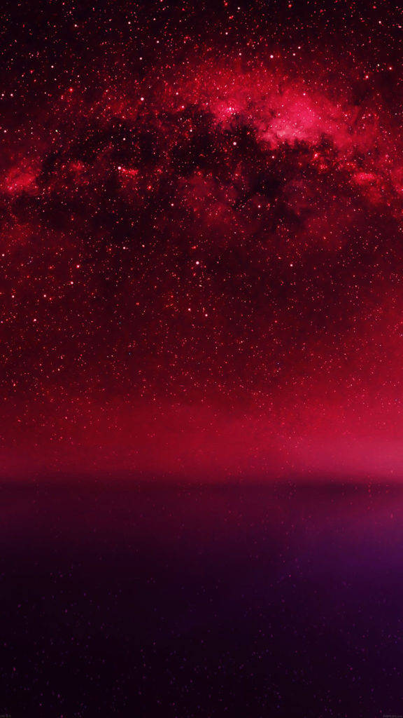 iPhone 動態 桌布 壁紙 — 在黑暗地平線上方，一個星系散發著深紅和紫色光芒的壯麗景色。