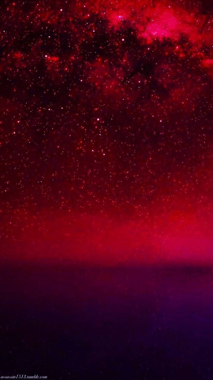 紅色美學動圖 桌布 壁紙 — 在黑暗地平線之上，充滿星星和星雲的令人驚嘆的紅色和紫色宇宙天空。