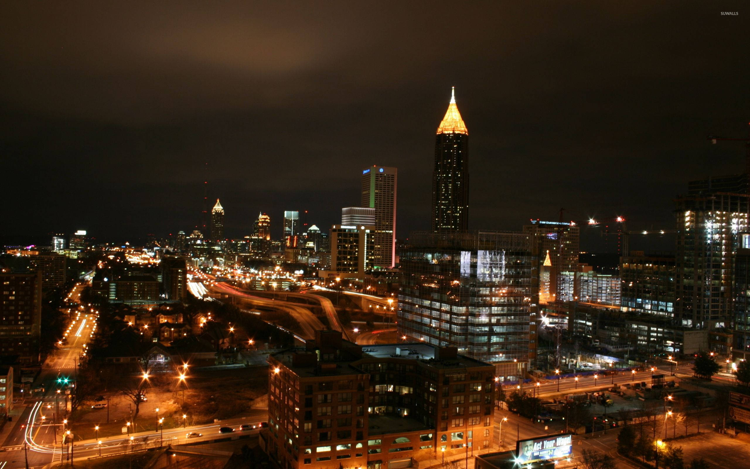 Atlanta 桌布 壁紙 — 在黑暗多雲的天空下，閃爍的摩天大樓和流動的車燈構成的充滿活力的夜間城市景觀。