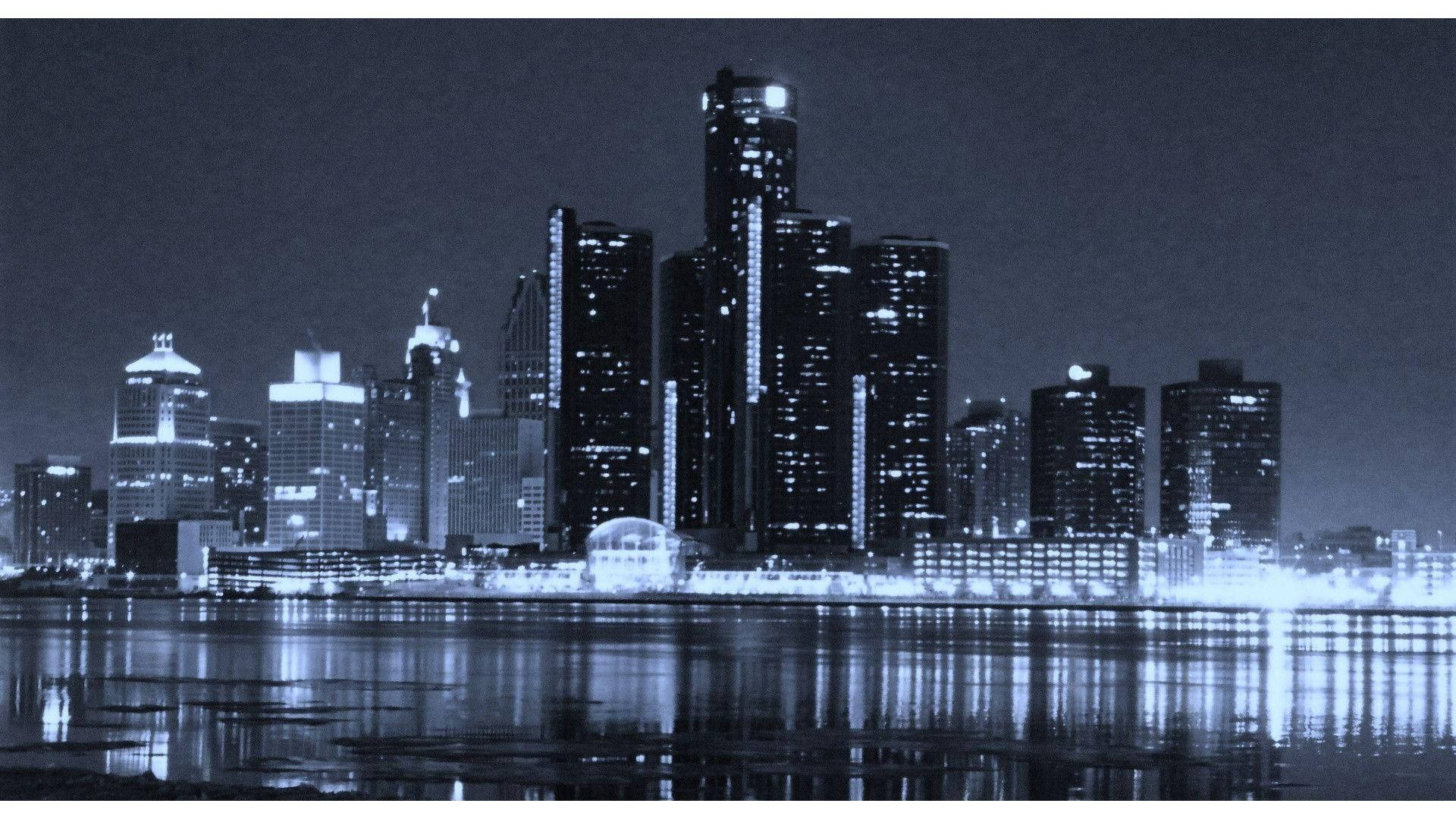 detroit 桌布 壁紙 — 在黑暗天空下，摩天大樓倒映在平靜水面上的單色夜景城市景觀。