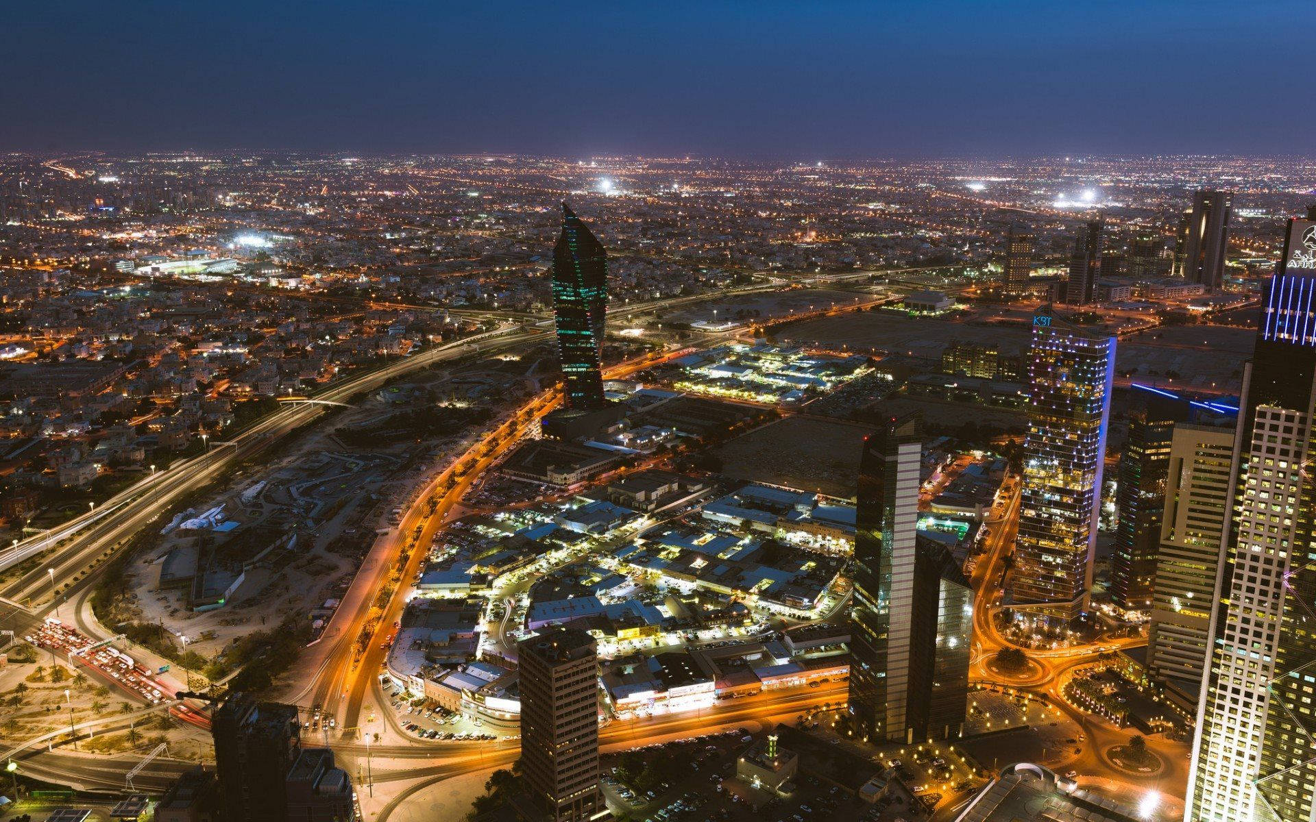 Kuwait 桌布 壁紙 — 在黑暗天空下，閃爍的摩天大樓和照明高速公路的廣闊城市景觀的鳥瞰夜景。