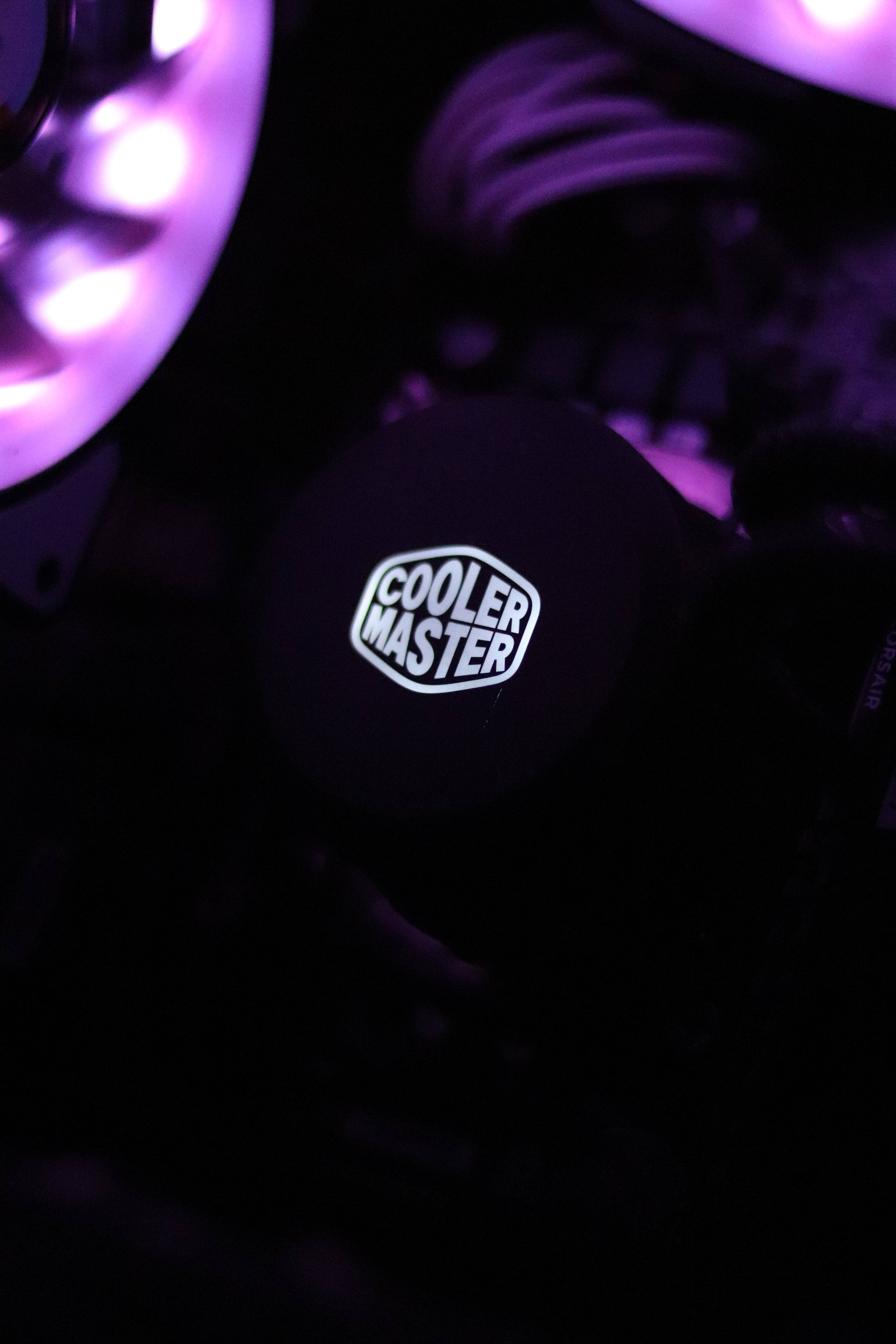 Black And Purple Phone 桌布 壁紙 — 在黑暗的PC機箱中，一個Cooler Master品牌的CPU散熱器蓋在紫色LED燈光下發光的特寫。