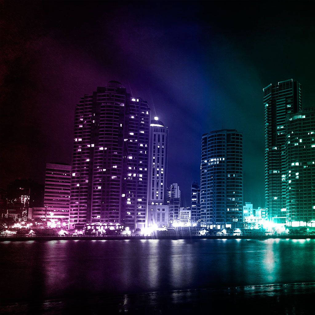 Skyscraper 桌布 壁紙 — 在黑暗的天空下，霓虹燈照亮的高樓大廈倒映在平靜的水面上，構成充滿活力的夜景。