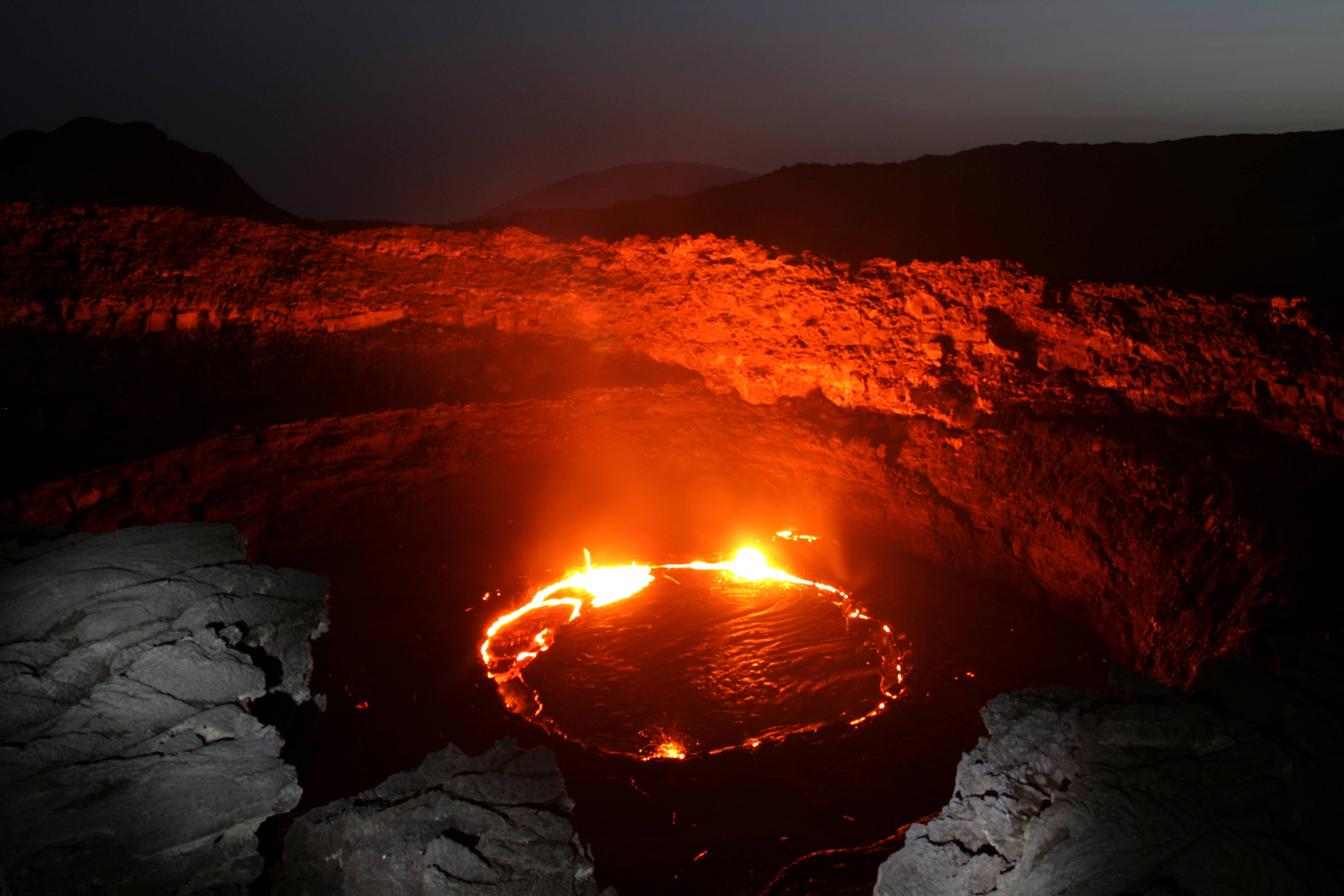 Ethiopia 桌布 壁紙 — 在黑暗的暮色天空下，火山口內一個發光的熔岩湖在脈動。