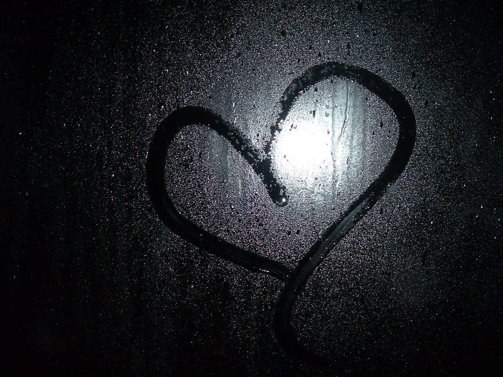 Dark Love 桌布 壁紙 — 在黑暗的窗戶上，用雨水畫出一個心形，明亮的光線從其中心穿過。