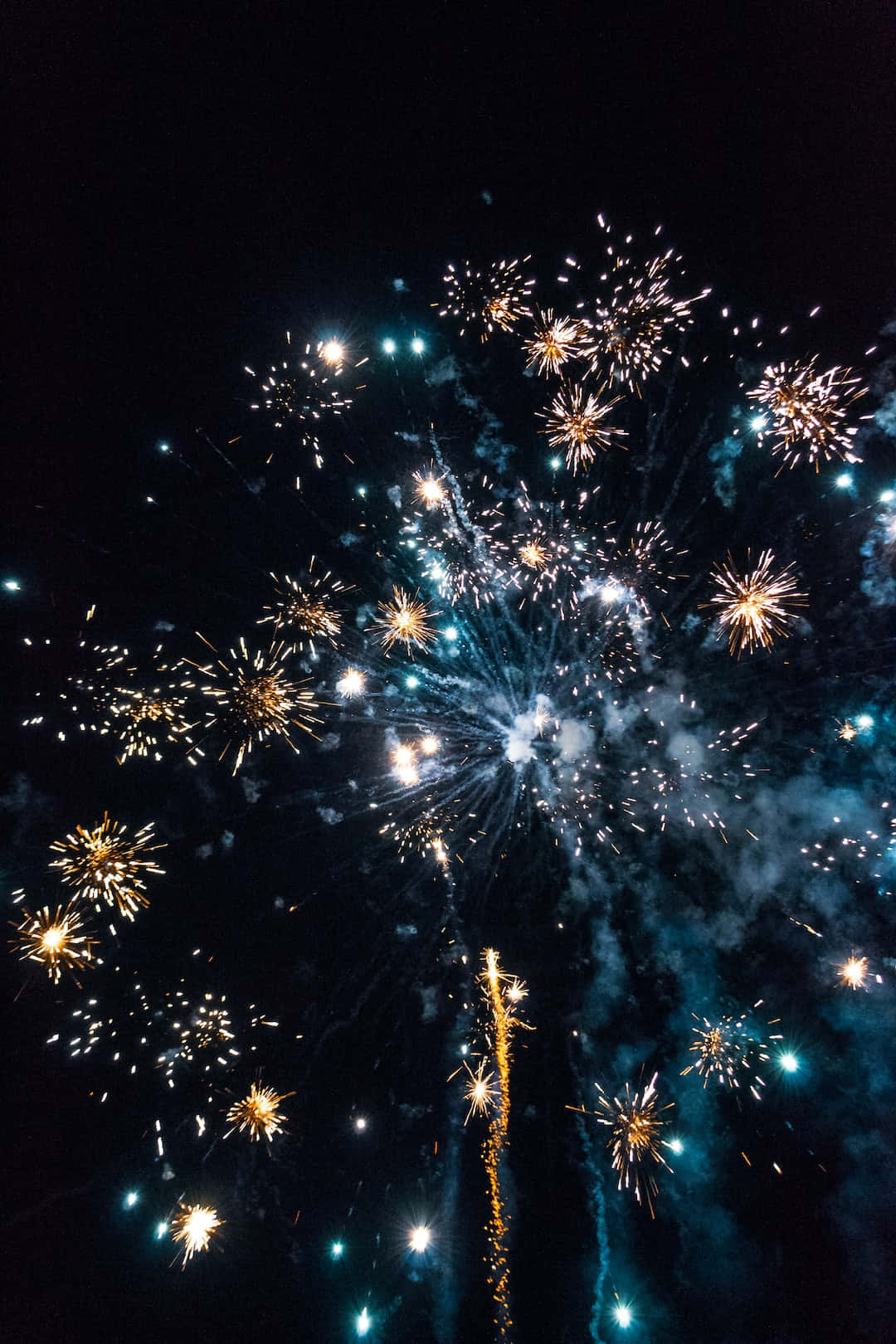 Fireworks 桌布 壁紙 — 在黑暗的背景下，絢麗的煙火在夜空中綻放出金色和藍色的光芒。