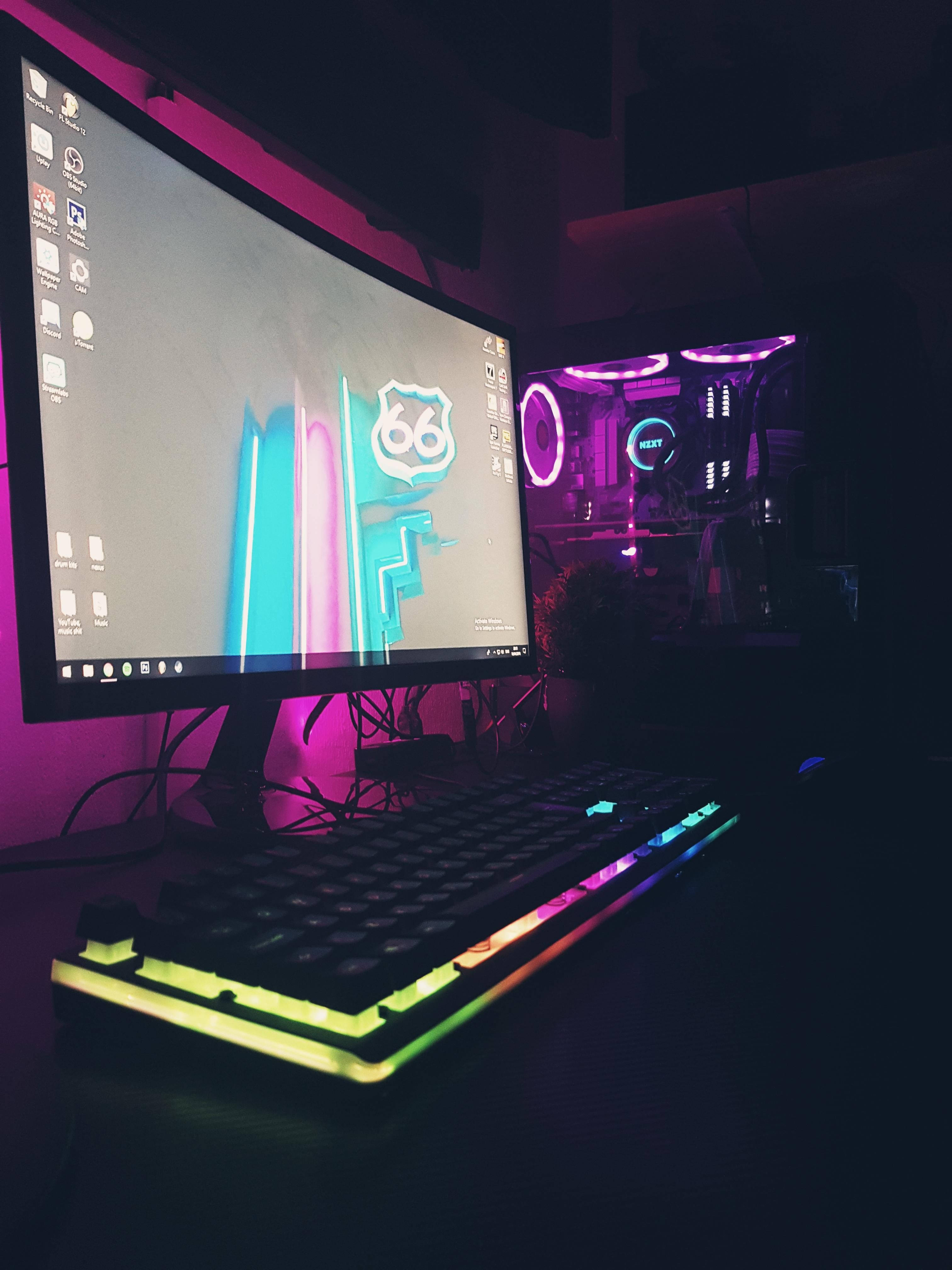 LED 桌布 壁紙 — 在黑暗的遊戲設置中，發光的RGB鍵盤和曲面顯示器在紫色環境光下顯示Route 66壁紙。