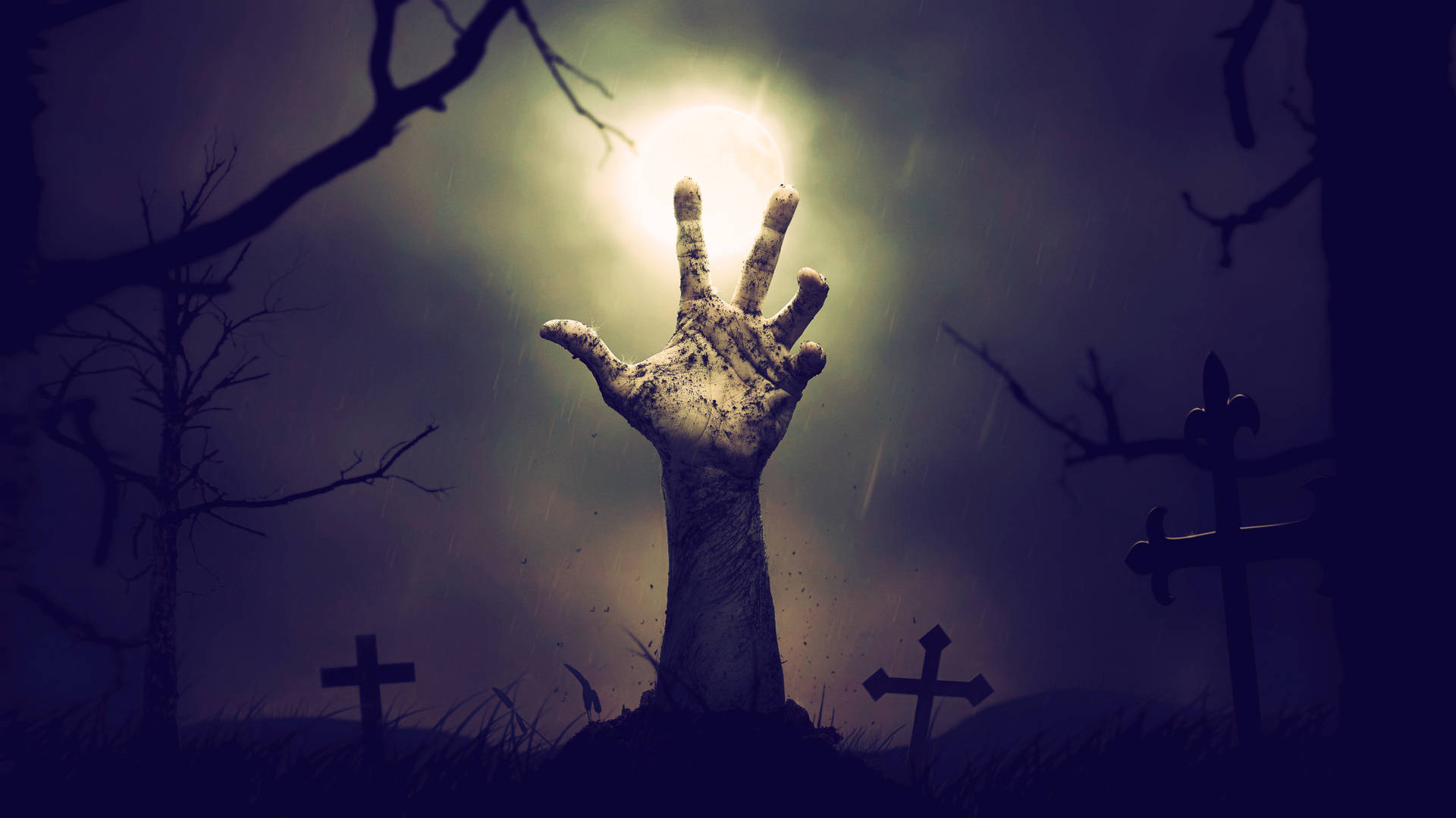 Zombie 桌布 壁紙 — 在黑暗的雨夜墓地中，一隻殭屍手從發光的滿月下的墳墓中爆出，周圍有光禿的樹木和十字架。