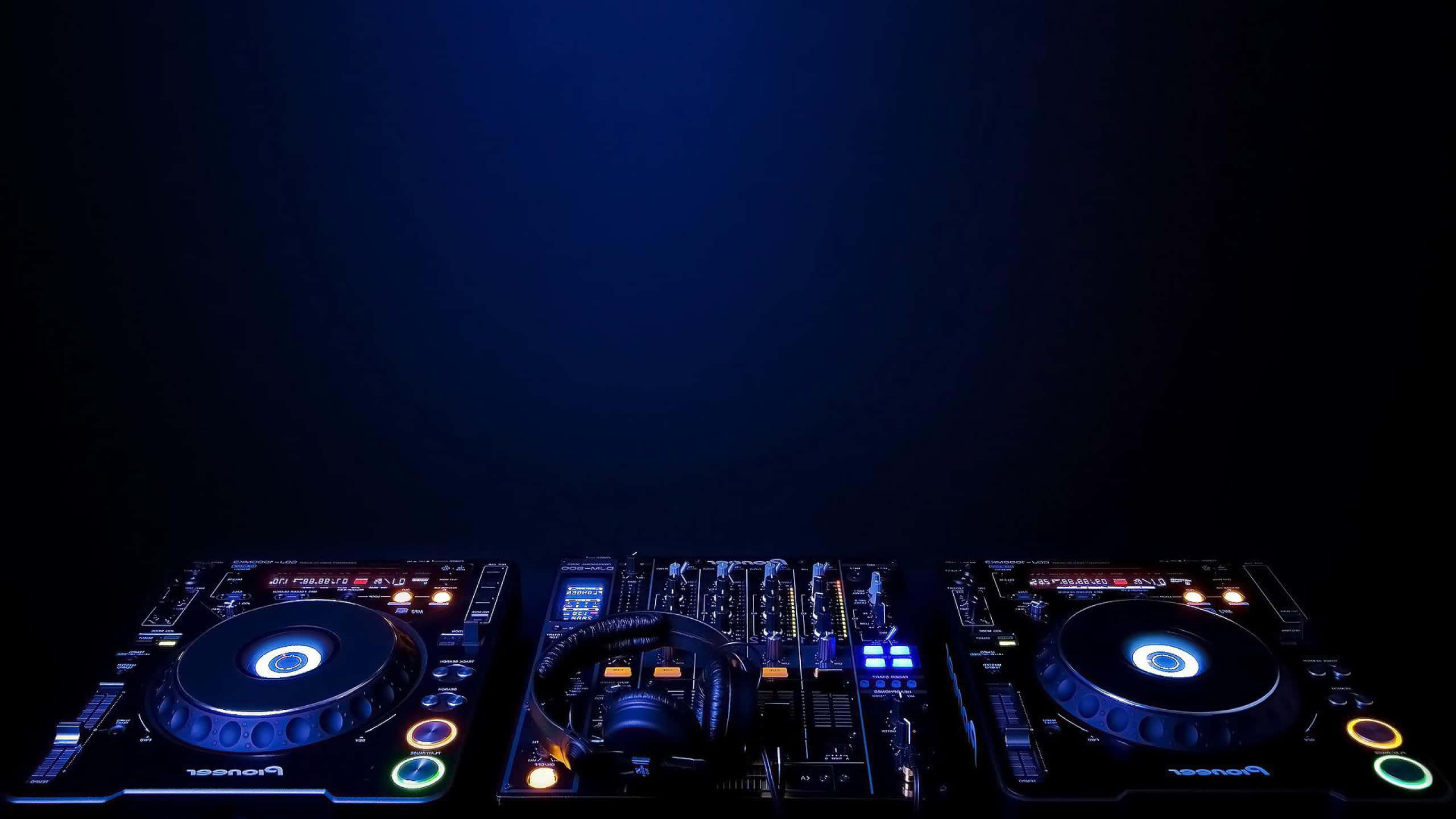 DJ 桌布 壁紙 — 在黑暗背景上帶有發光藍色和橙色燈光的DJ設置。