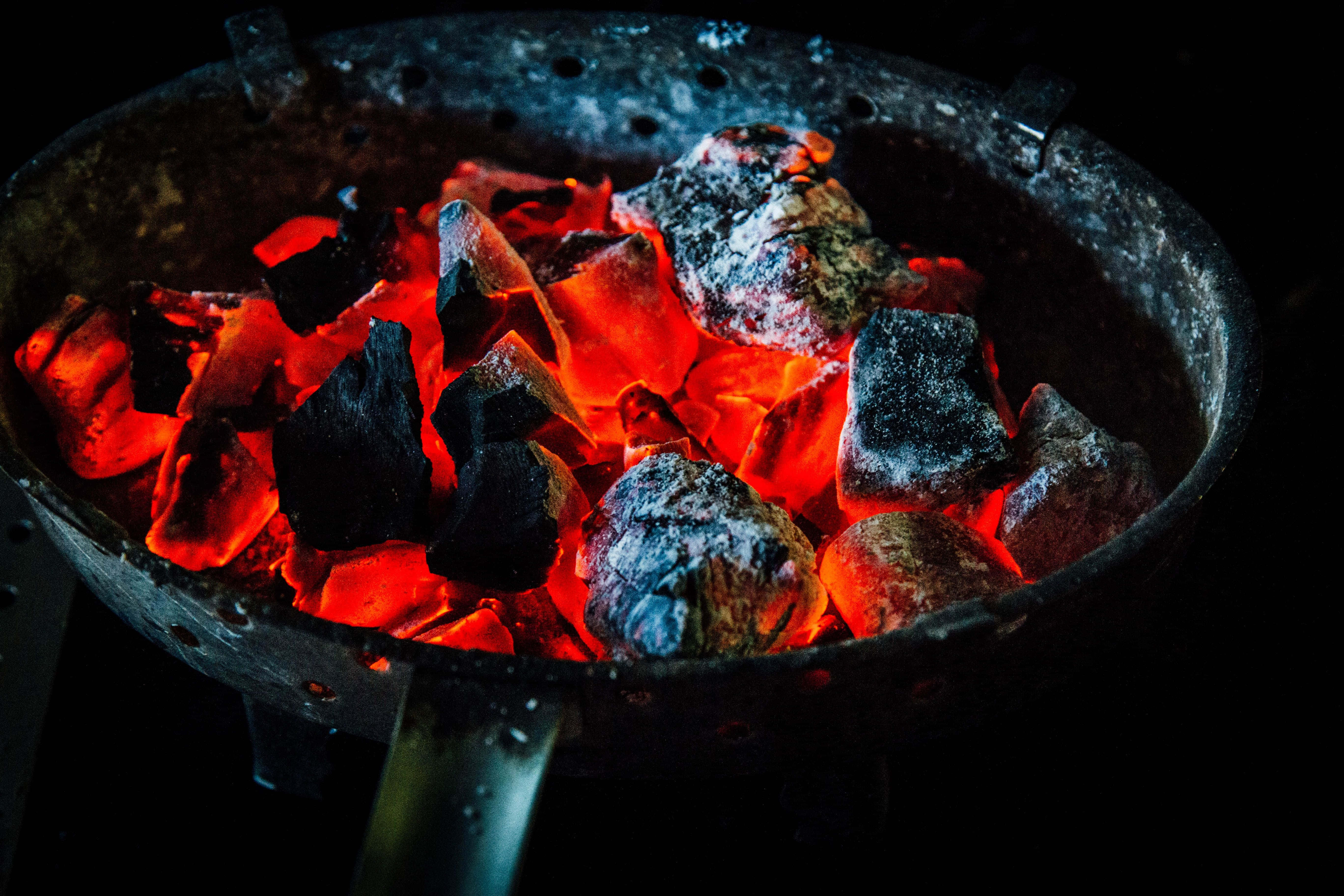 Charcoal 桌布 壁紙 — 在黑暗背景下，風化的金屬烤架內，發光的紅色木炭餘燼散發著溫暖。