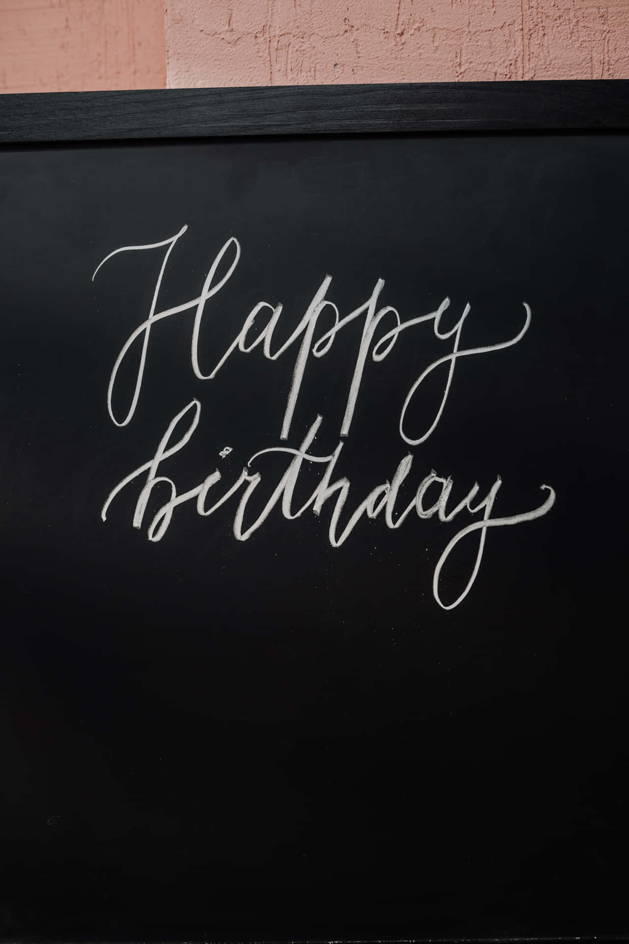生日快樂 桌布 壁紙 — 在黑板上優雅的白色草書「Happy Birthday」，上方有紋理的粉紅色牆壁。