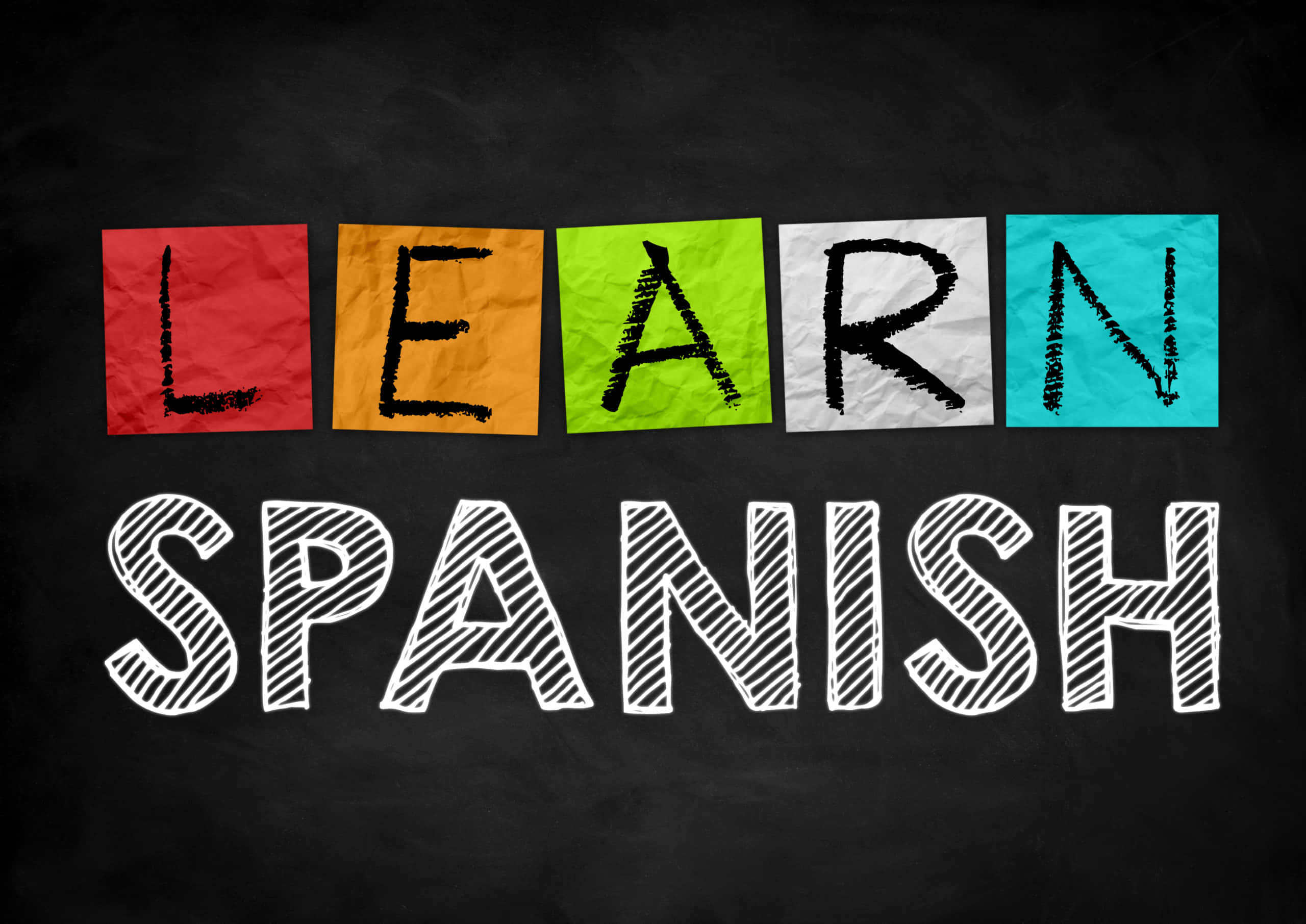 Spanish 桌布 壁紙 — 在黑板上用粉筆風格拼出「SPANISH」上方「LEARN」的大膽彩色紙字母。