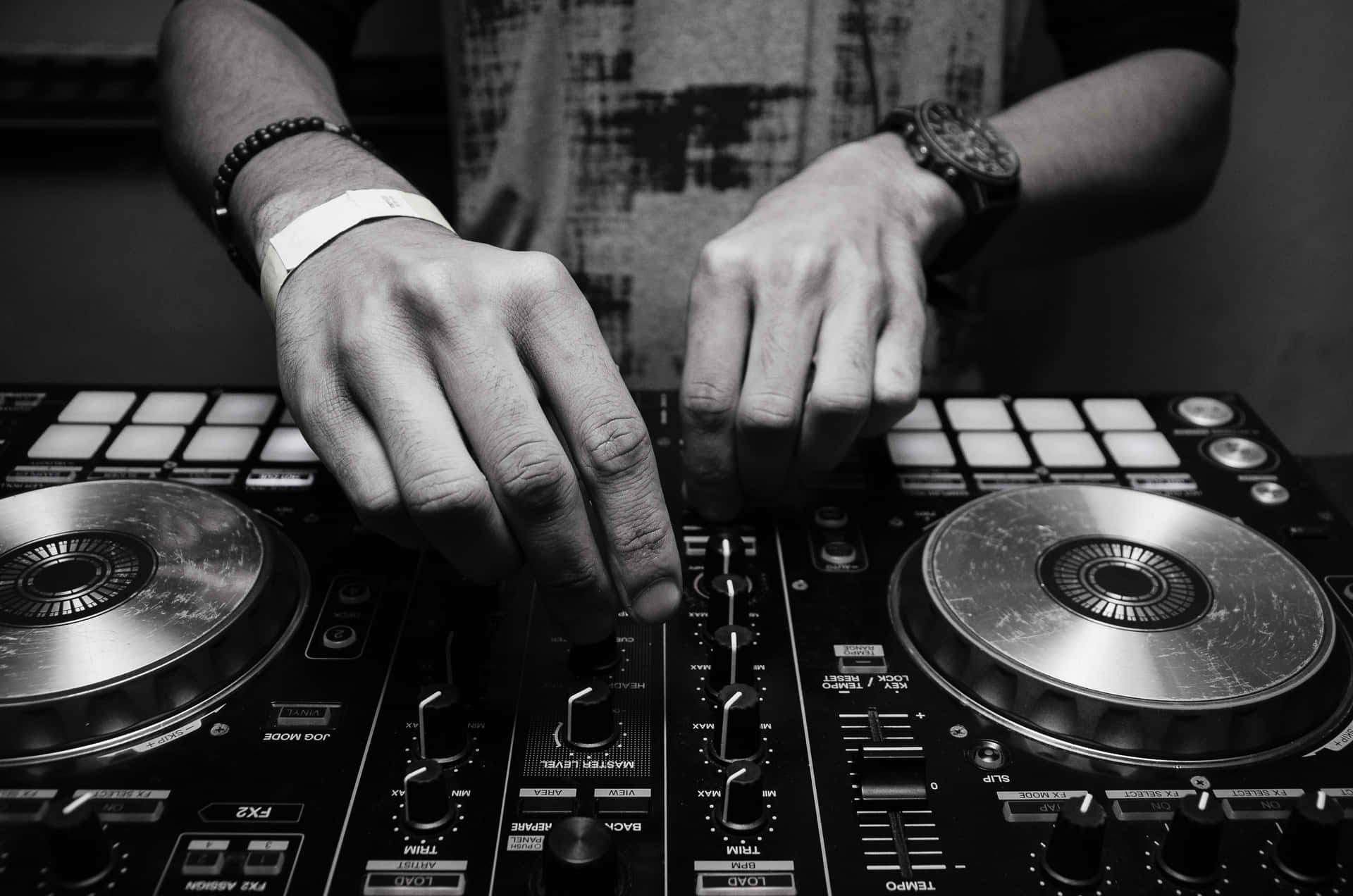 DJ 桌布 壁紙 — 在黑白照片中，DJ 的雙手熟練地操作專業混音器上的旋鈕和唱盤。