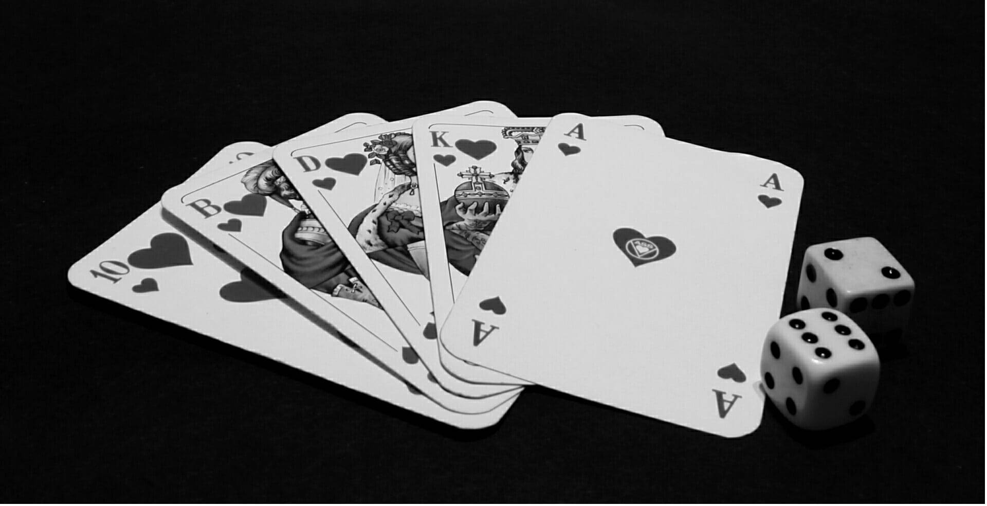 Playing Cards 桌布 壁紙 — 在黑色背景上以扇形展開的撲克牌和骰子的單色圖案。