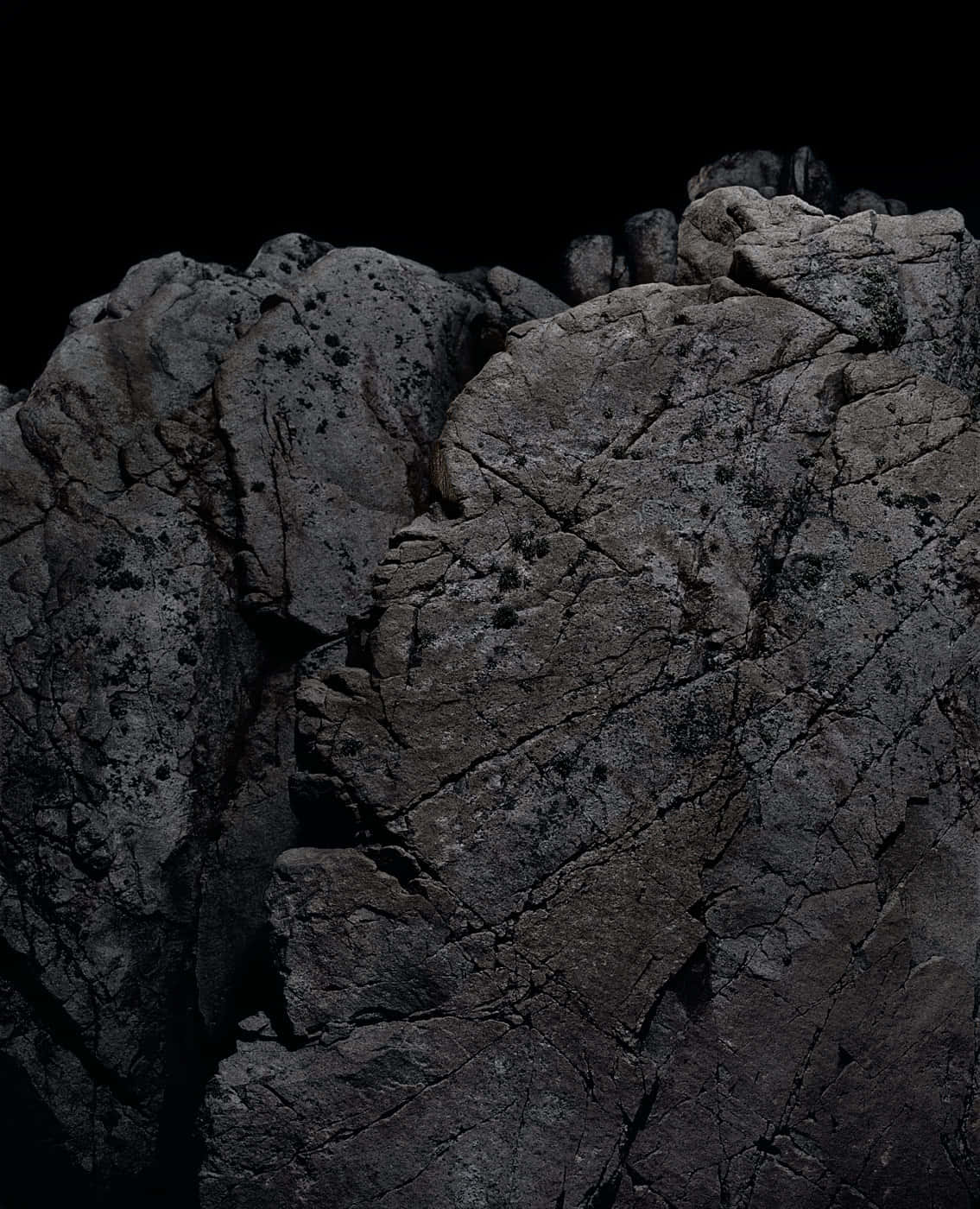 Dark Rock 桌布 壁紙 — 在黑色虛空背景下，強烈燈光照射下粗糙、有紋理岩石的戲劇性特寫。