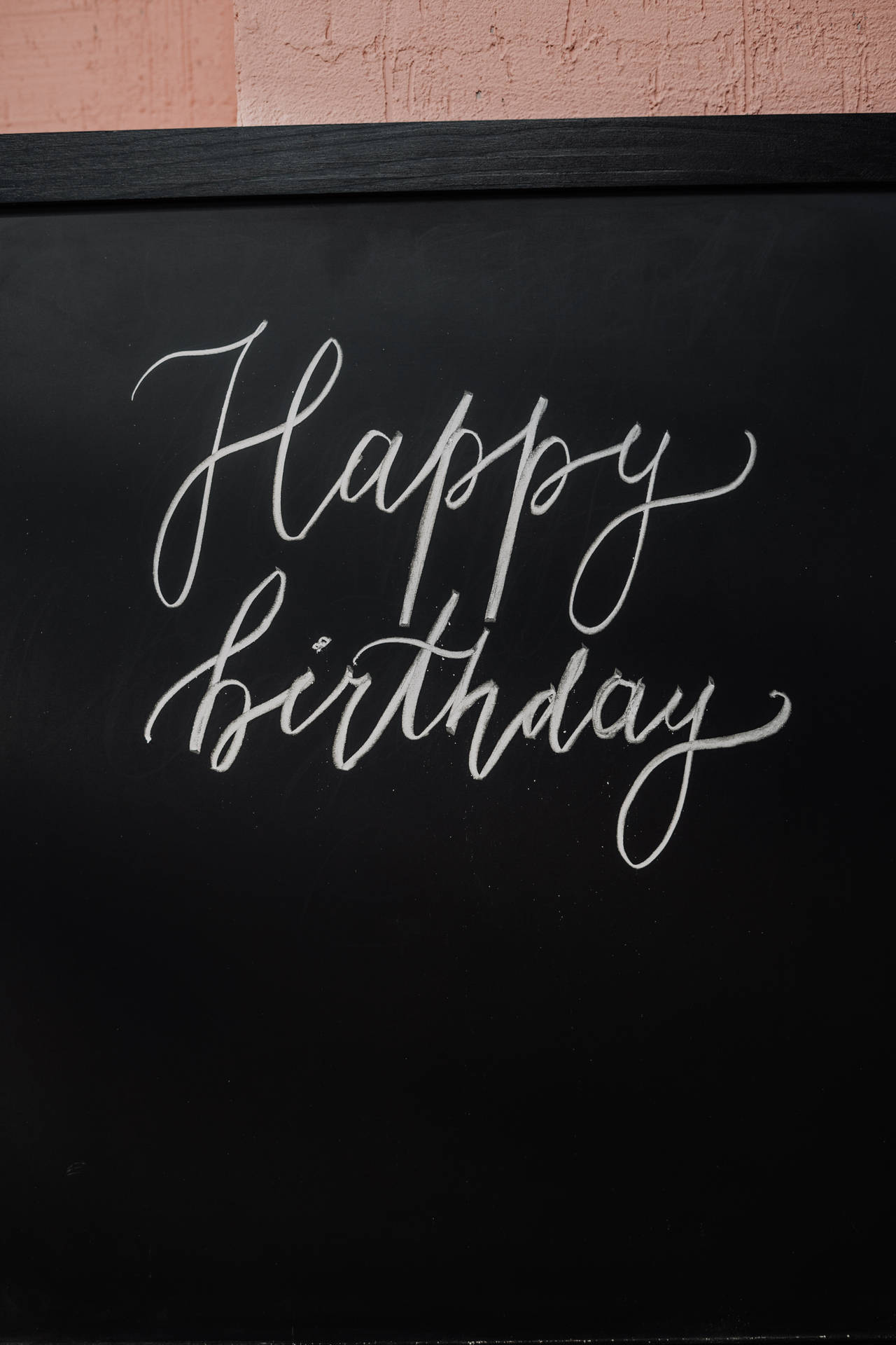 Happy Birthday 以白色草書寫在黑色黑板上。