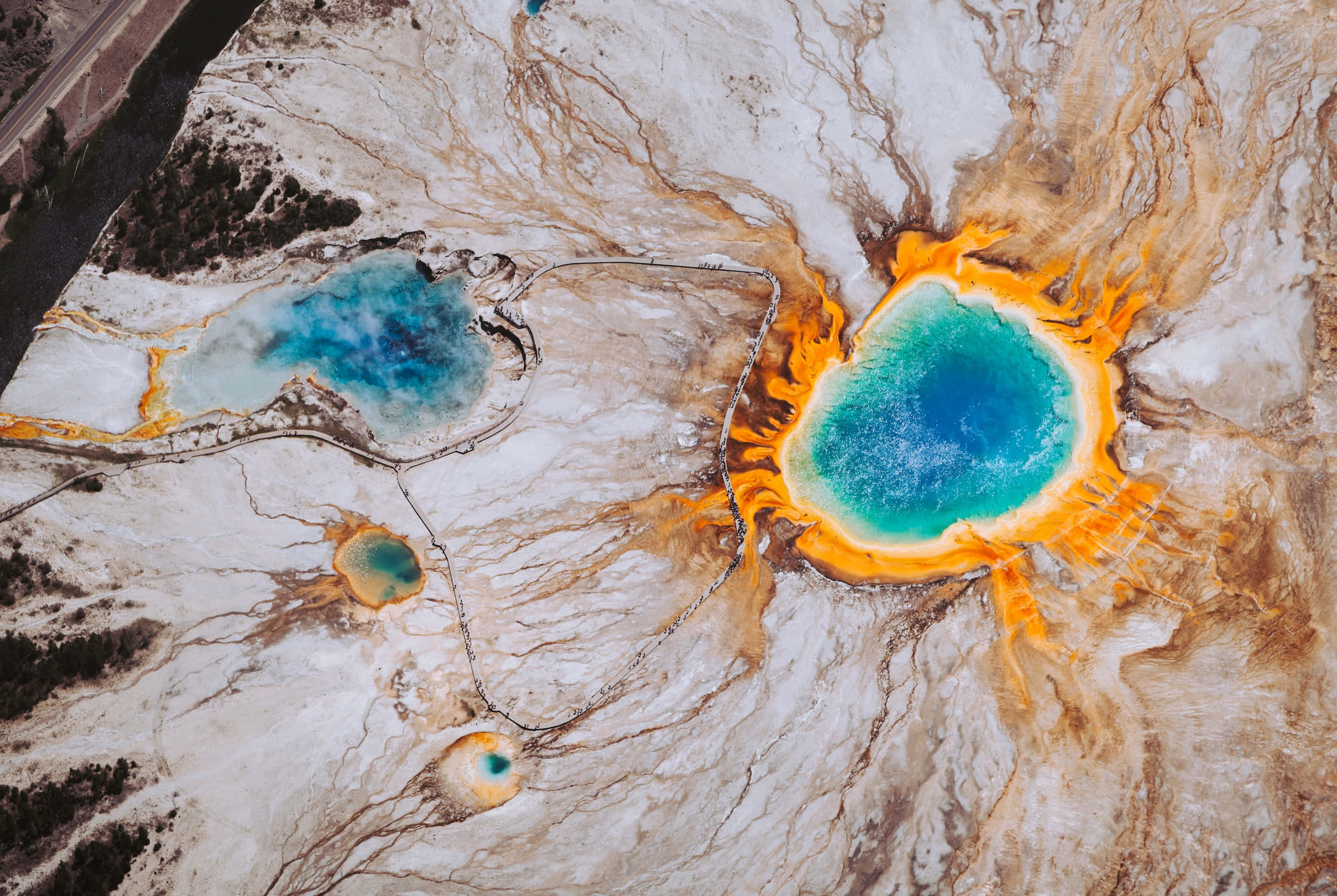 Yellowstone Geysers 桌布 壁紙 — 地熱景觀中，充滿活力的綠松色溫泉被旋轉的橙色和白色礦物沉積物包圍的鳥瞰圖。
