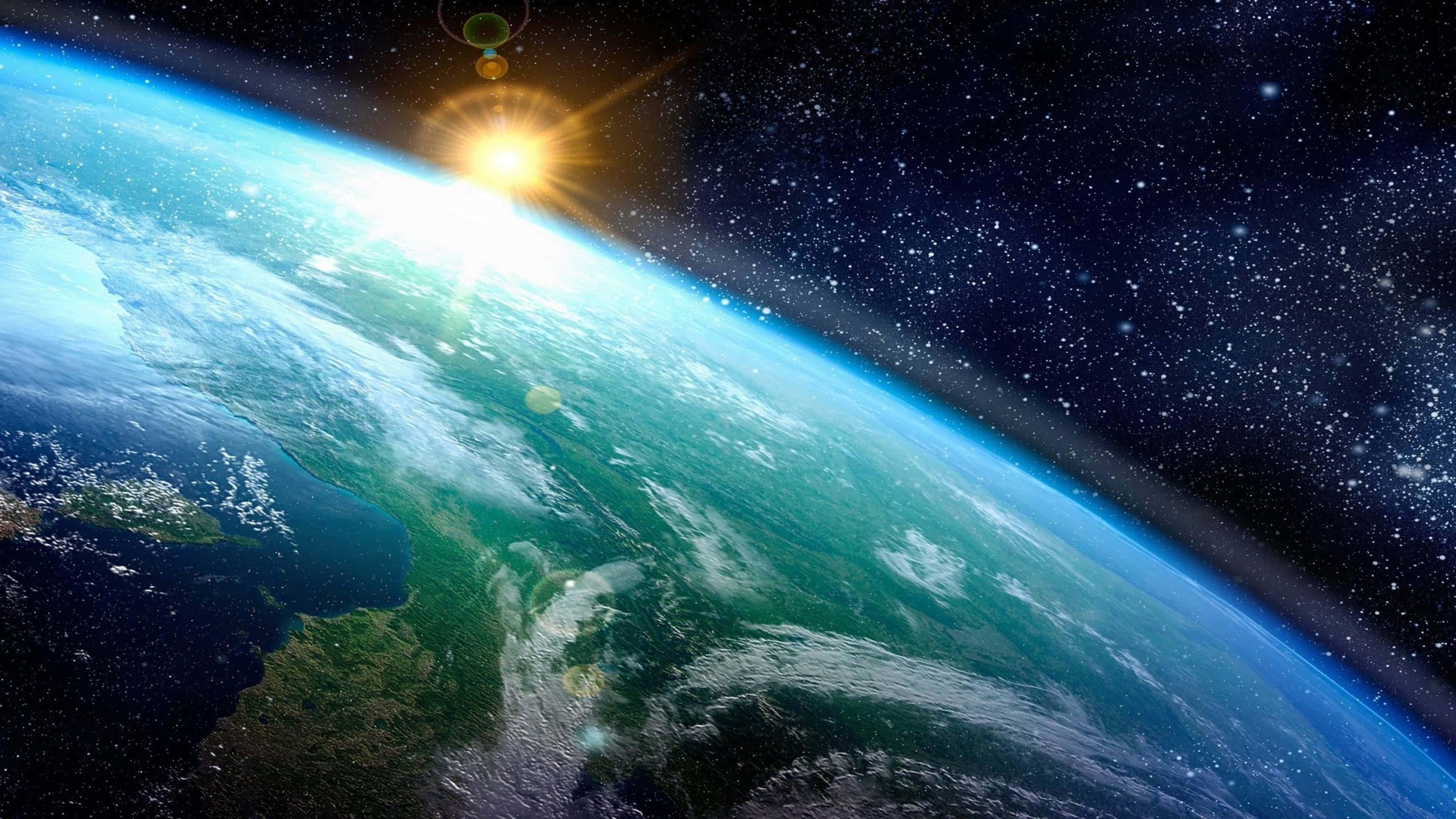 4K 超高清 桌布 壁紙 — 地球在太空中雄偉地彎曲，陽光爆發照亮海洋、大陸和虛空中閃爍的星星。